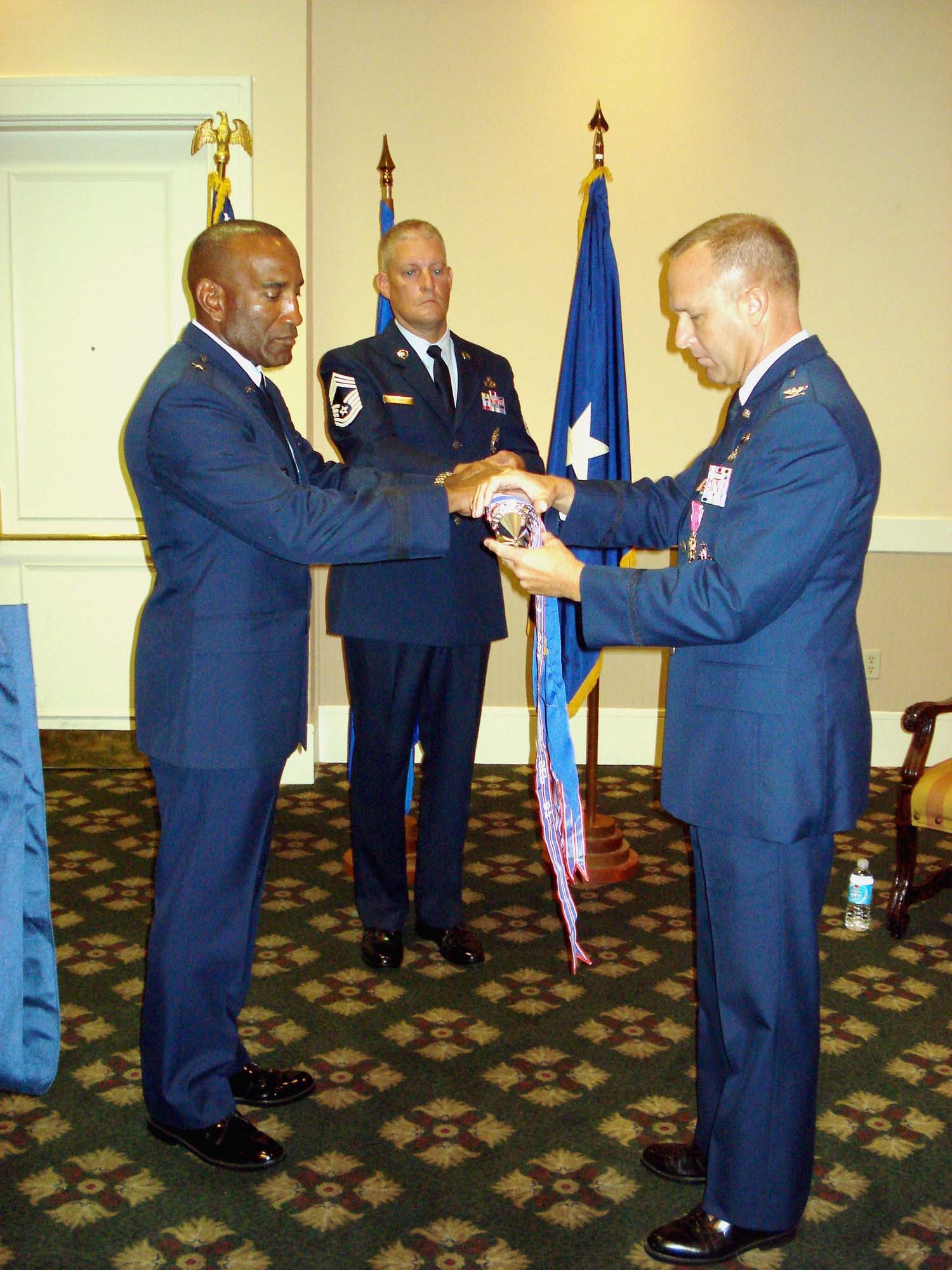 Chief Master Sgt. Michael Suchy holds the 367th Recruiting Group guidon as Col. Michael Brice (right), group commander, and Brig. Gen. A.J. Stewart (left), Air Force Recruiting Service commander, officially retire the group flag Sept. 12. The 367th Recruiting Group is being deactivated as part as a larger reorganization within AFRS. (Photo by Tech. Sgt. Laura Stickle)