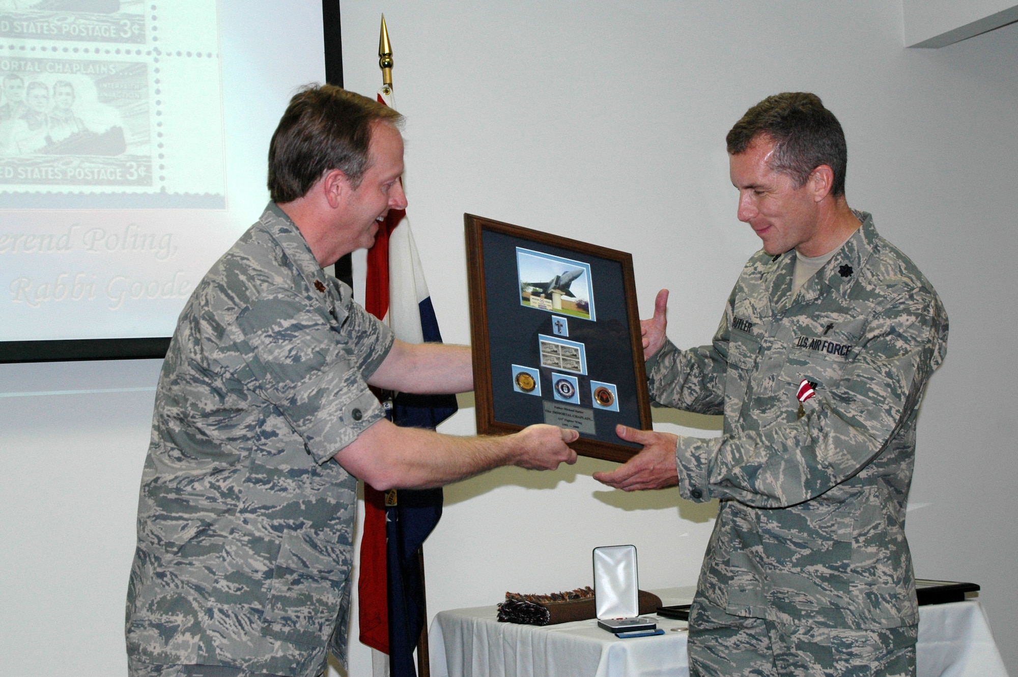 Maj. Scott Doby, 131st Fighter Wing chaplain, presents Lt. Col. Michael Butler, 131st Fighter Wing chaplain, with a framed photo that commemorates Chaplain Butler's time with the Fighter Wing. (Photo by Master Sgt. Mary-Dale Amison)