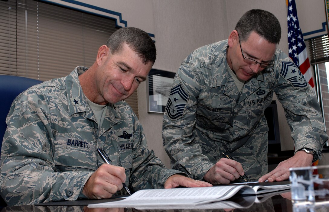 LANGLEY AIR FORCE BASE, Va. -- Brig. Gen. Mark Barrett, 1st Fighter Wing commander and Chief Master Sgt. Kevin Slater, 1st FW command chief, sign checks to donate money to Langley’s 2008 Combined Federal Campaign Sept. 23.  The program provides federal employees with an opportunity to support local national and international charities. The CFC runs from Oct. 1 to Nov. 7. (U.S. Air Force photo/Airman 1st Class Zachary Wolf)