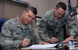 LANGLEY AIR FORCE BASE, Va. -- Brig. Gen. Mark Barrett, 1st Fighter Wing commander and Chief Master Sgt. Kevin Slater, 1st FW command chief, sign checks to donate money to Langley’s 2008 Combined Federal Campaign Sept. 23.  The program provides federal employees with an opportunity to support local national and international charities. The CFC runs from Oct. 1 to Nov. 7. (U.S. Air Force photo/Airman 1st Class Zachary Wolf)
