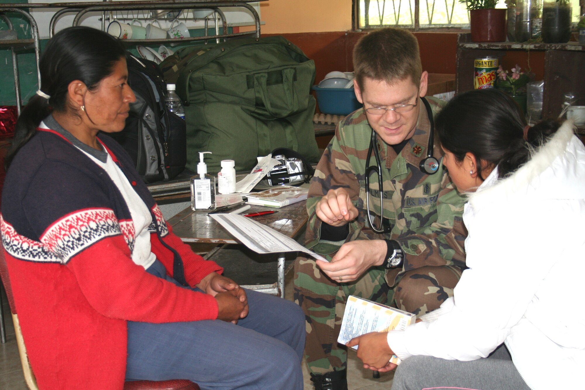Maj. (Dr.) Robert Holmes, 81st Medical Operations Squadron medical director for infectious diseases, speaks to an interpreter as he treats a patient.