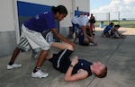 Elena Gumbs (left) helps Chris Crabbe in a stretching exercise prior to a Randolph High cross country practice Sept. 22. The Ro-Hawks have run four meets so far and the duo has paced the team with some of the best times posted. (U.S. Air Force photo by Rich McFadden)