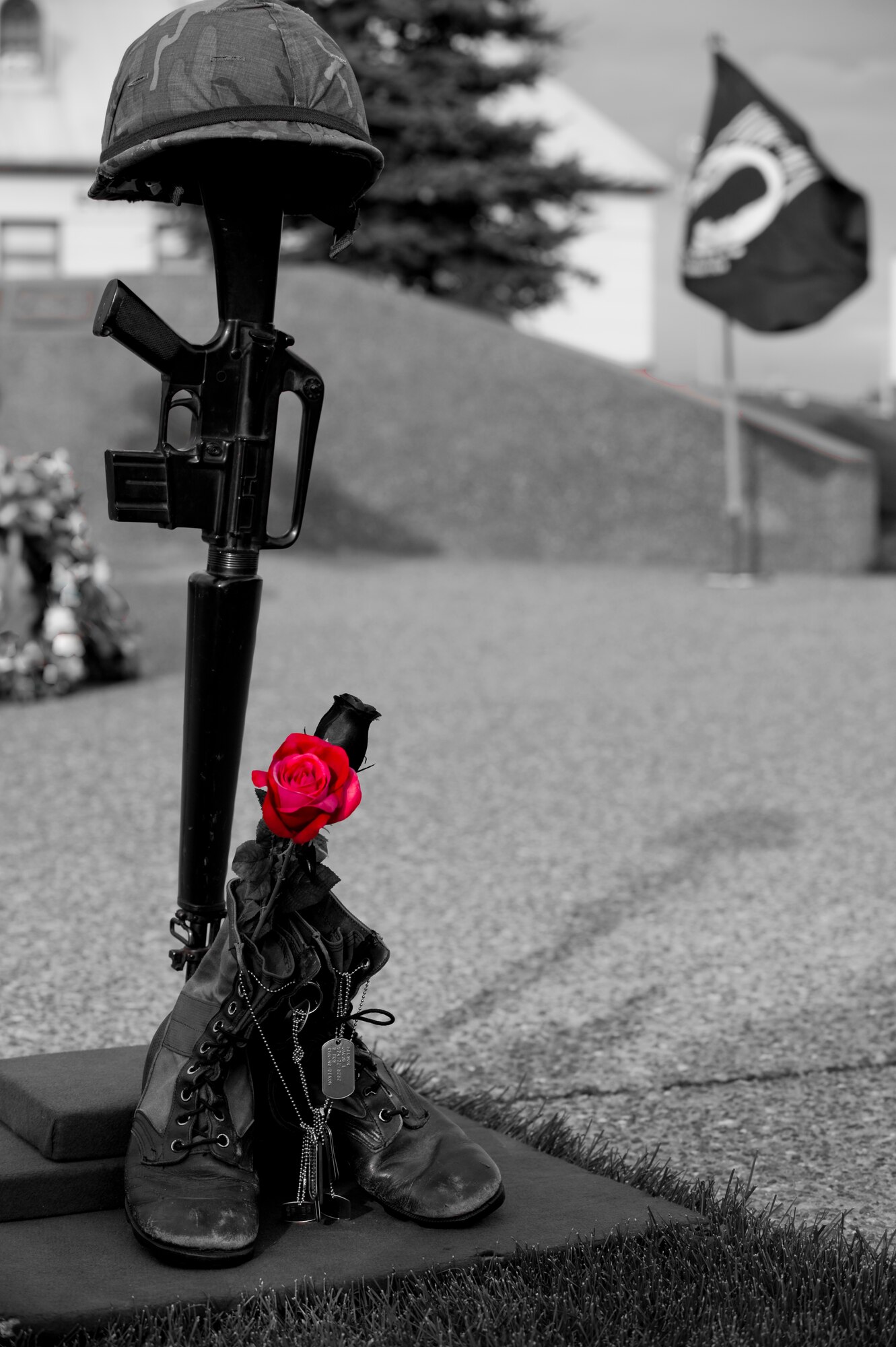 ELMENDORF AIR FORCE BASE, Alaska -- A Fallen Warrior Memorial stands upright as the POW/MIA flag waves in the background during the POW/MIA ceremony Sept. 19. The Fallen Warrior Memorial consists of items that represent different aspects of the battle field. The rifle represents the warriors weapon, the helmet represents the armor, the boots and nametags represents the fallen warrior itself, and the single rose represents the countries love, honor and mourning for the fallen warrior. (U.S. Air Force photo illustration/Staff Sgt. Joshua Garcia)