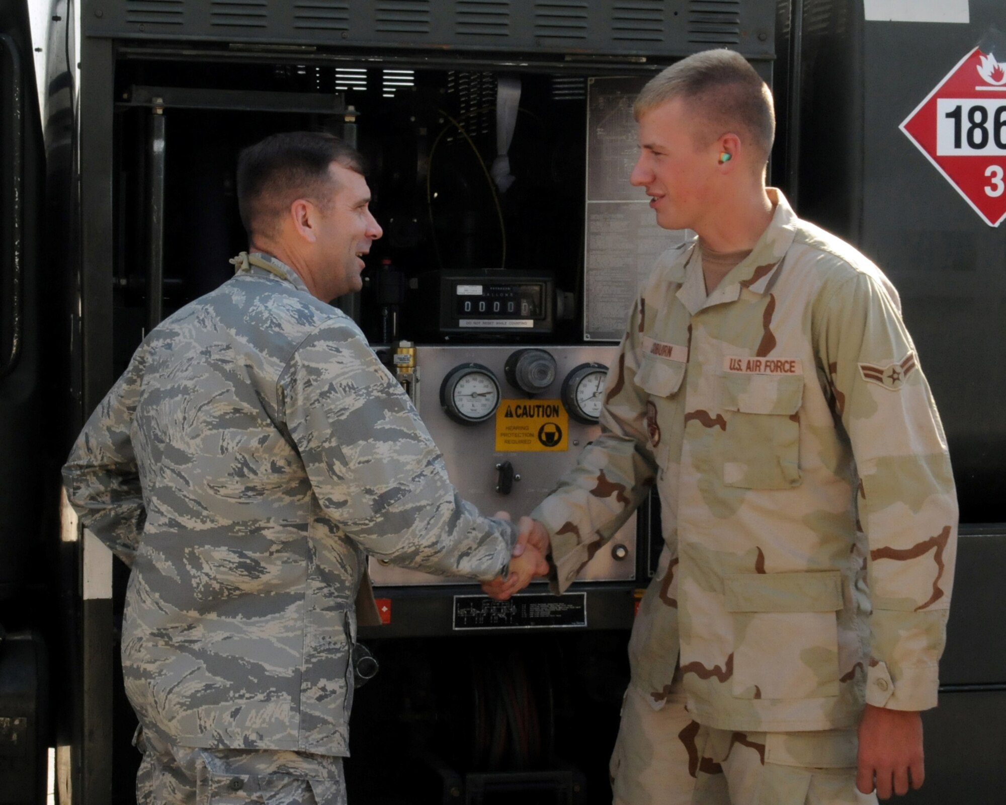 MANAS AIR BASE, KRYGYZ REPUBLIC -- Airman 1st Class Gregory Coburn, a fuels distribution operator with the 376th Expeditionary Logistics Readiness Squadron's Petroleum, Oil and Lubricants Flight, is congratulated by Col. Christopher Bence, 376th Air Expeditionary Wing commander, as he reaches a unique deployment milestone, Sept. 1; two million gallons of fuel pumped. Airman Coburn, who is deployed from Whiteman Air Force Base, Mo., is one of only four Airmen at the wing to reach the impressive feat during a four month deployment. Colonel Bence was on hand to "coin" Airman Coburn for his hard work and dedication to supporting the wing's air refueling mission. (Air Force photo / Senior Airman Ruth Holcomb)