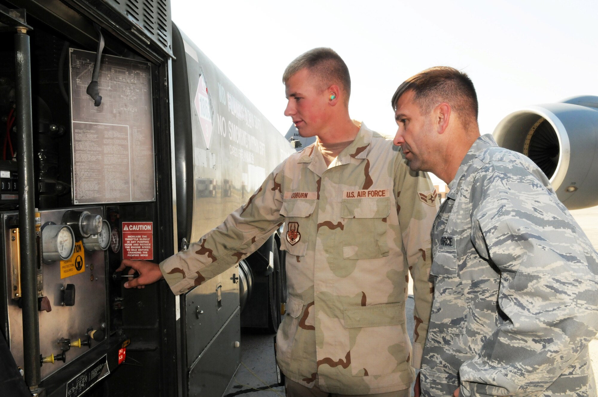 MANAS AIR BASE, KRYGYZ REPUBLIC -- Airman 1st Class Gregory Coburn, a fuels distribution operator with the 376th Expeditionary Logistics Readiness Squadron's Petroleum, Oil and Lubricants Flight, explains his job to Col. Christopher Bence, 376th Air Expeditionary Wing commander, as he reaches a unique deployment milestone, Sept. 1; two million gallons of fuel pumped. Airman Coburn, who is deployed from Whiteman Air Force Base, Mo., is one of only four Airmen at the wing to reach the impressive feat during a four month deployment. Colonel Bence was on hand to "coin" Airman Coburn for his hard work and dedication to supporting the wing's air refueling mission. (Air Force photo / Senior Airman Ruth Holcomb)
