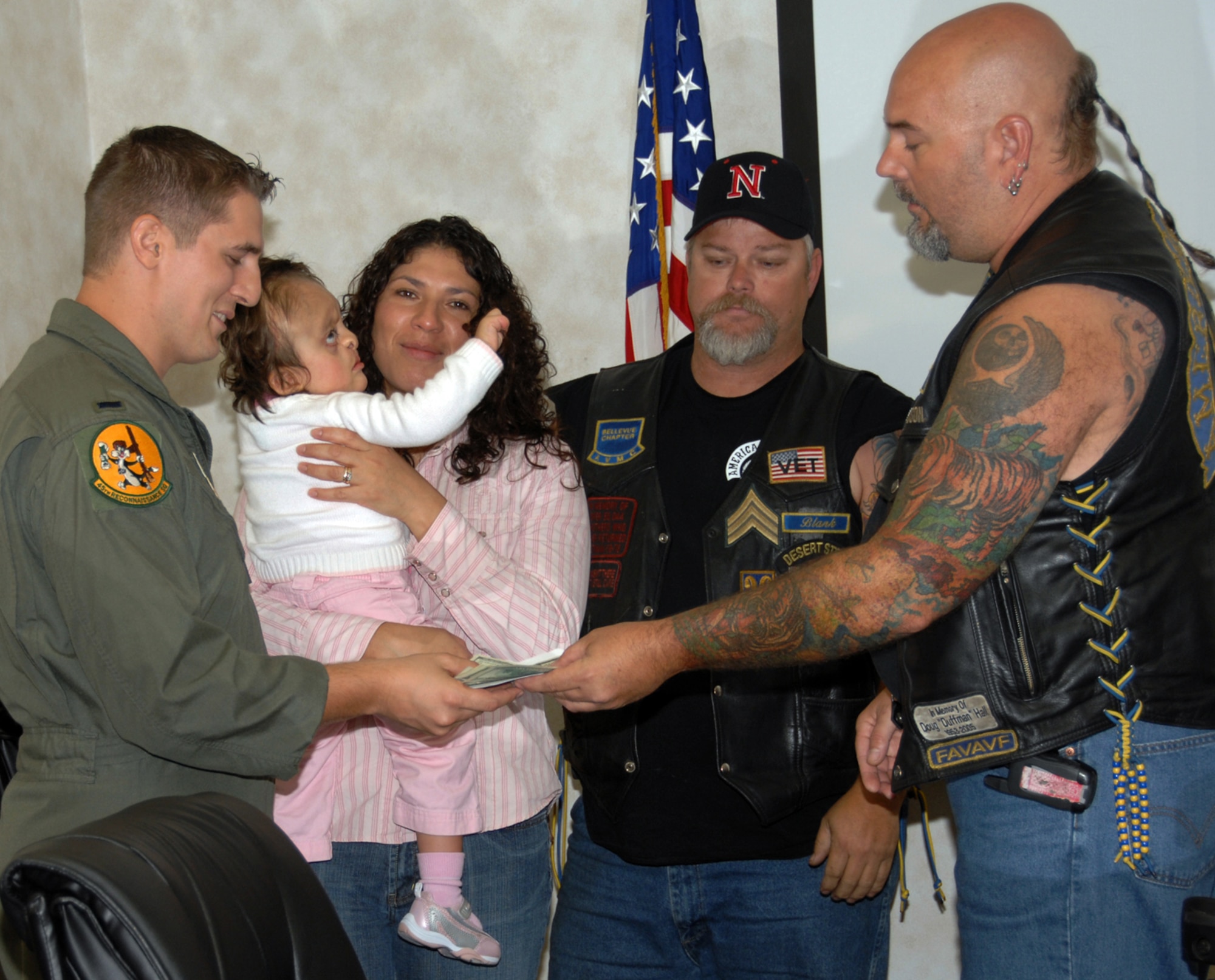 James Whitmire (right), president for Bellevue’s Chapter of the American Veterans Motorcycle Club, and another AVMC member present a donation to 1st Lt. Matthew Todd, 45th Reconnaissance Squadron electronic warfare officer, and his family recently. The donation, raised during the AVMC’s annual poker run, will help pay bills incurred from much needed surgeries for the Todd’s daughter. (U.S. Air Force Photo By Kendra Williams) 