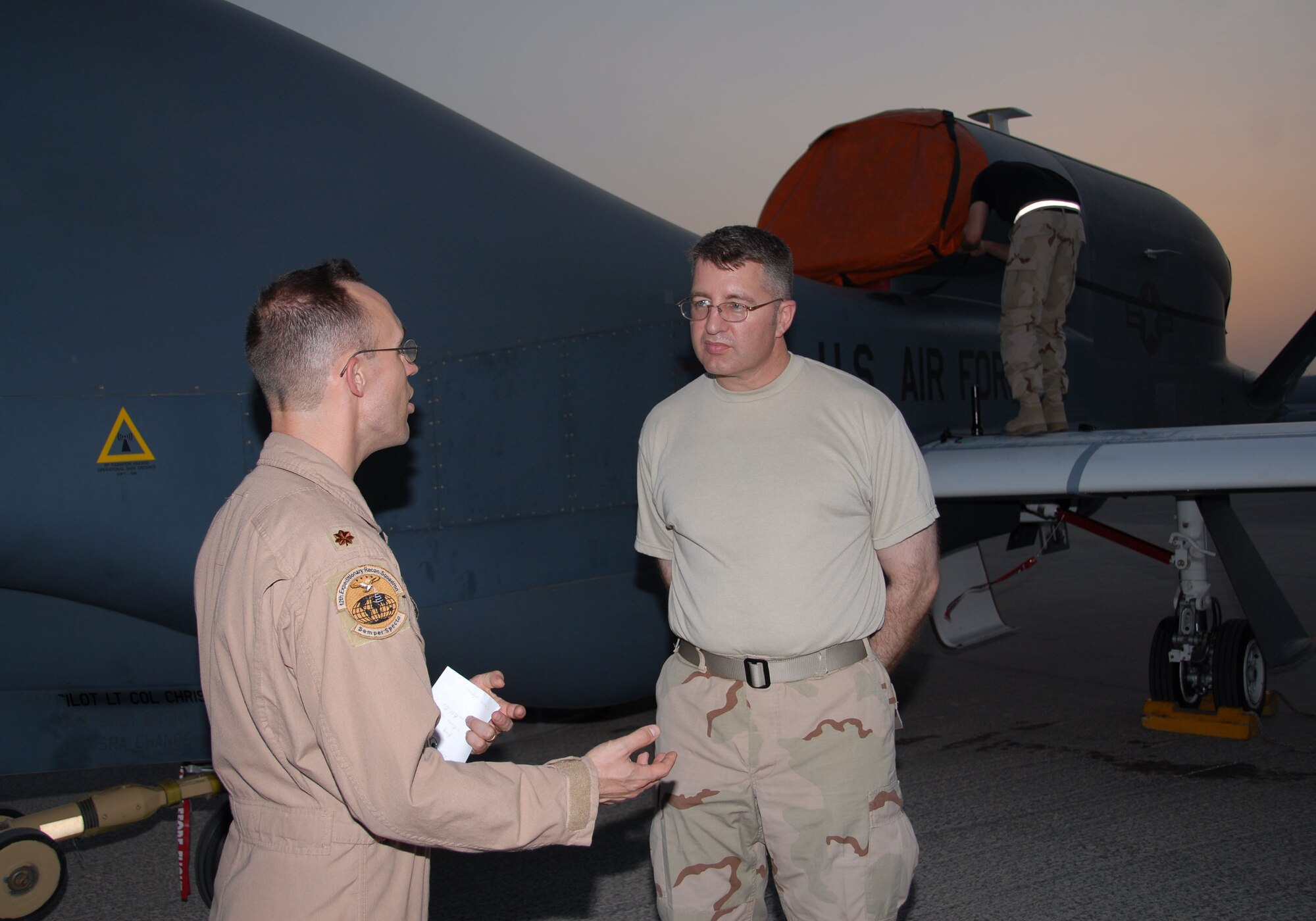 SOUTHWEST ASIA -- Maj. Rob Matlock, the 12th Expeditionary Reconnaissance Squadron commander and Global Hawk pilot, discusses the first operational transatlantic joint-launched Global Hawk with the 380th Air Expeditionary Wing Historian, Lane Bourgeios here Sept. 21. The unmanned aircraft was only on the ground for about five hours after its historic flight from Pax River, Md., Sept. 20 before being turned around and sent into the Area of Operations. The operational flight also marked the first time two Global Hawks were being flown simultaneously in neighboring theaters in support of Operations Iraqi and Enduring Freedom. Mr. Bourgeios is deployed here from Randolph Air Force Base, Texas. (U.S. Air Force photo/Tech. Sgt. Denise Johnson)(released)