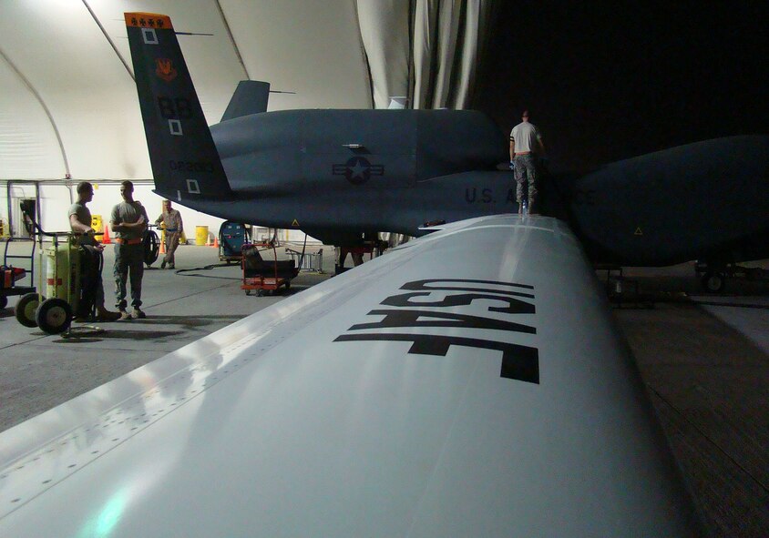 SOUTHWEST ASIA -- Pilots and maintainers with the 380th Air Expeditionary Wing tend to the first operationally-flown transatlantic Global Hawk here Sept. 21. It was also the first joint-launch in the history of the aircraft. The unmanned aircraft was only on the ground for about five hours after its historic flight from Pax River, Md., Sept. 20 before being turned around and sent into the Area of Operations. The operational flight also marked the first time two Global Hawks were being flown simultaneously in neighboring theaters in support of Operations Iraqi and Enduring Freedom. (U.S. Air Force photo/Tech. Sgt. Denise Johnson)(released)