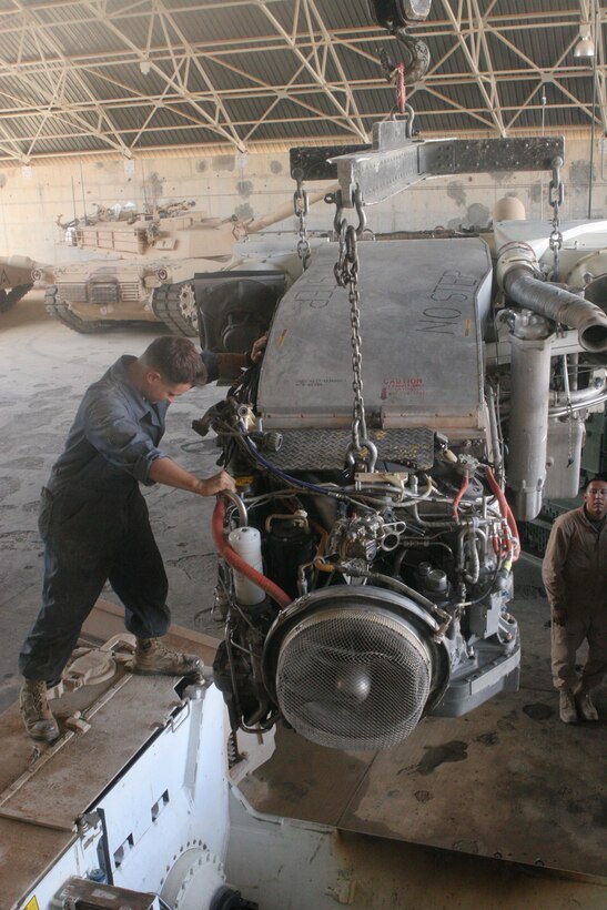 Cpl. Ryan J. Sharkey, 24, from Vista, Calif., who is a tank driver with Company A, 4th Tank Battalion, Regimental Combat Team 5, guides a turbine engine into a M1A1 Abrams main battle tank at Al Asad Air Base, Iraq, Sept. 23. The dust and heat of the Iraqi desert makes it necessary for the Marines with Company A to meticulously check their tanks to guarantee that they are combat ready.