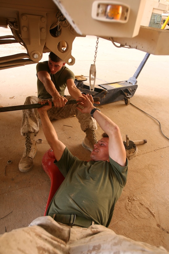 Cpl. Taylor Marple (back), 21, a shop chief, helps Lance Cpl. Dustin O. Davis, a floor chief, torque a wrench beneath the axles of a Mine Resistant Ambush Protected vehicle at Al Asad Air Base, Iraq, Sept. 27.  Both Marines are with Motor Transportation Platoon, Headquarters and Service Co., 3rd Battalion, 7th Marine Regiment, Regimental Combat Team 5.  The Motor-T Marines work on everything from HMMWVs to trucks to the Marine Corpsâ?? newest Mine Resistant Ambush Protected vehicle.::r::::n::