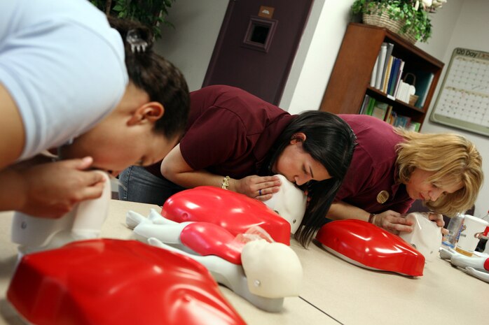 NELLIS AIR FORCE BASE, Nev. -- Megan Hurtado, Danielle Gutierrez and Betty Gura (left to right) perform cardiopulmonary resuscitation techniques during the Child Development Center quarterly staff training day. Both CDC locations on base closed for the day, allowing staff members to refresh their skills and receive required training. (U.S. Air Force Photo by Lawrence R. Crespo)