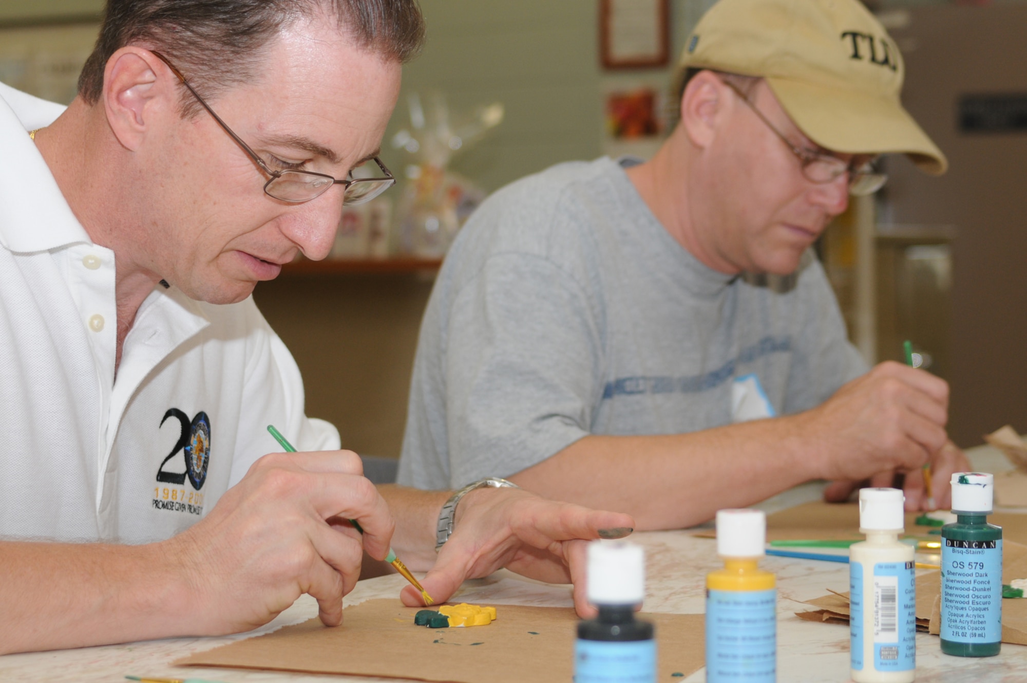 Col. Chris Valle, 81st Training Wing vice commander, and Col. Jeffrey Jackson, 81st Mission Support Group commander, paint ceramic magnolias at the arts and crafts center.  (U.S. Air Force photo by Kemberly Groue)