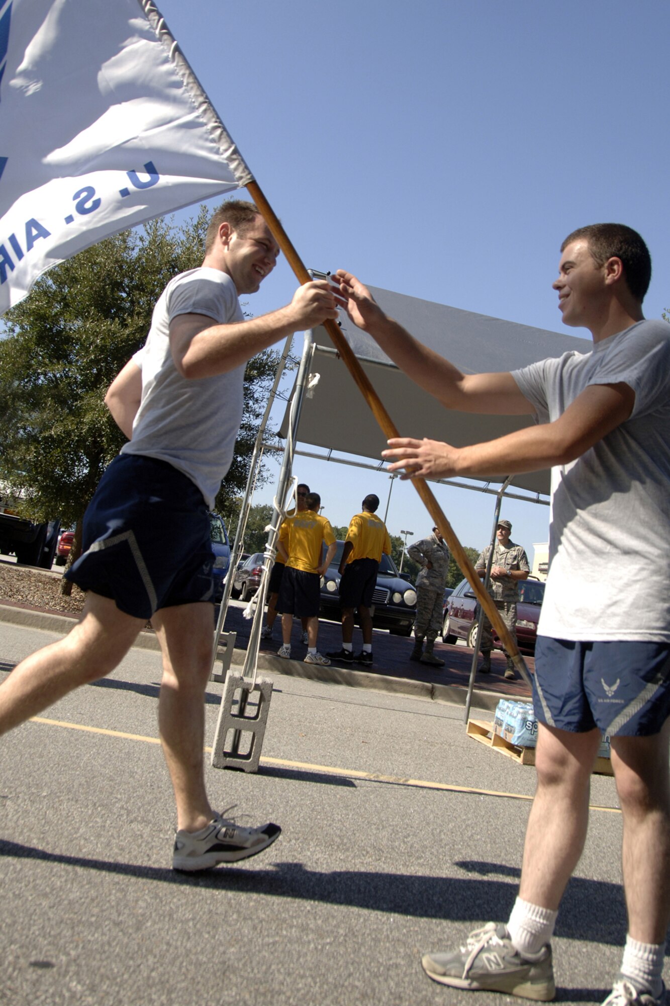 An Airman hands off the Air Force flag to a rested runner Sept. 24 at the base commissary during the POW/MIA 24-hour vigil run. Airmen from Charleston AFB were joined by service members and cadets representing the other branches of the military throughout the 24-hour period to honor United States military members taken as prisoners of war and those who are still missing in action. (U.S. Air Force photo/Airman 1st Class Timothy Taylor)