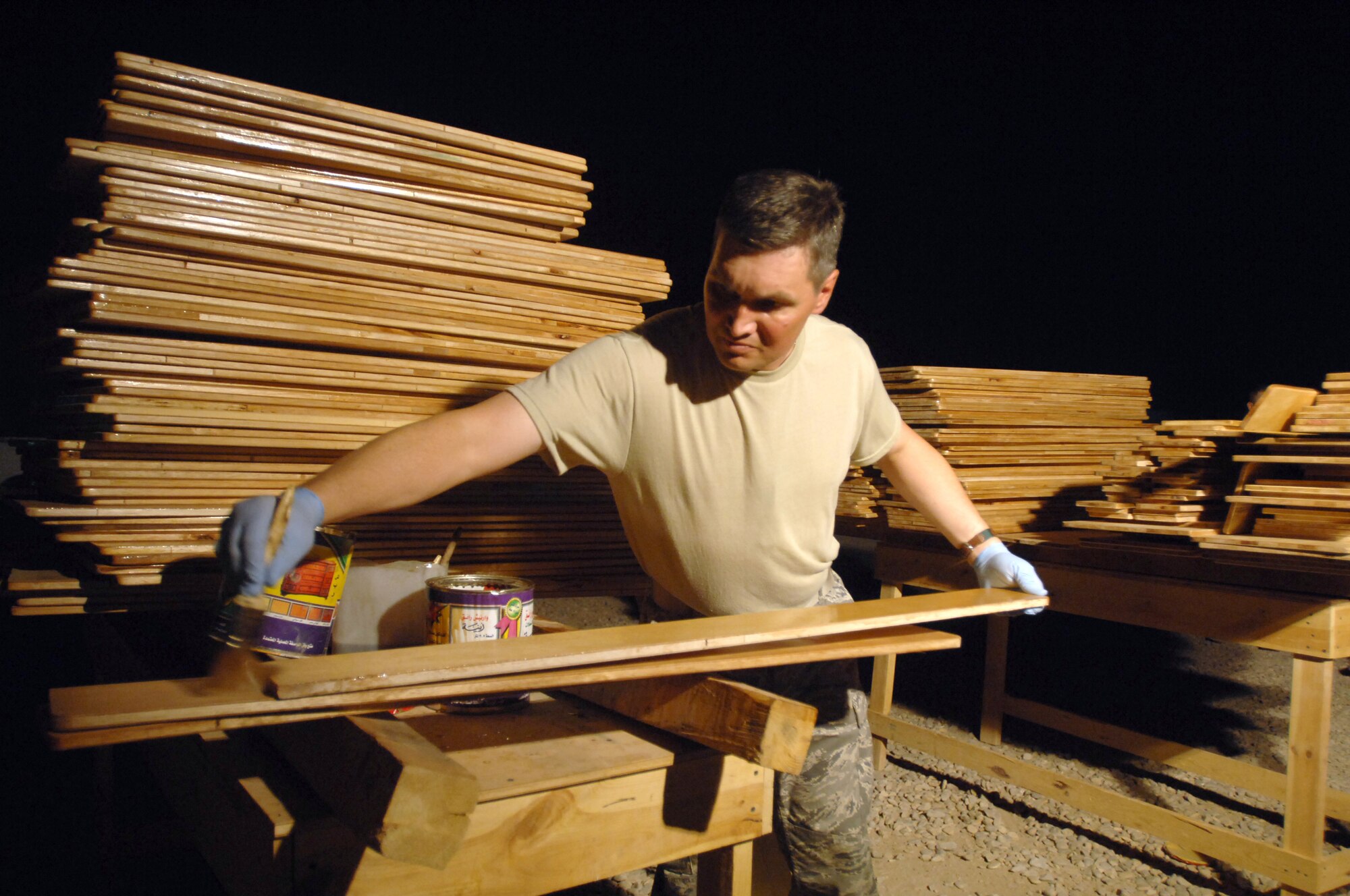 Chaplain (Maj.) John Painter, 407th Air Expeditionary Group chaplain, applies lacquer to a desk seat Sept. 18. He and others here volunteered to refurbish 150 desks that, once finished, 450 students from two Muthanna Province elementary schools will receive "new" desks. Painter is a reservist deployed from Charleston Air Force Base, S.C. (U.S. Air Force photo/Tech. Sgt. Francesca Popp)