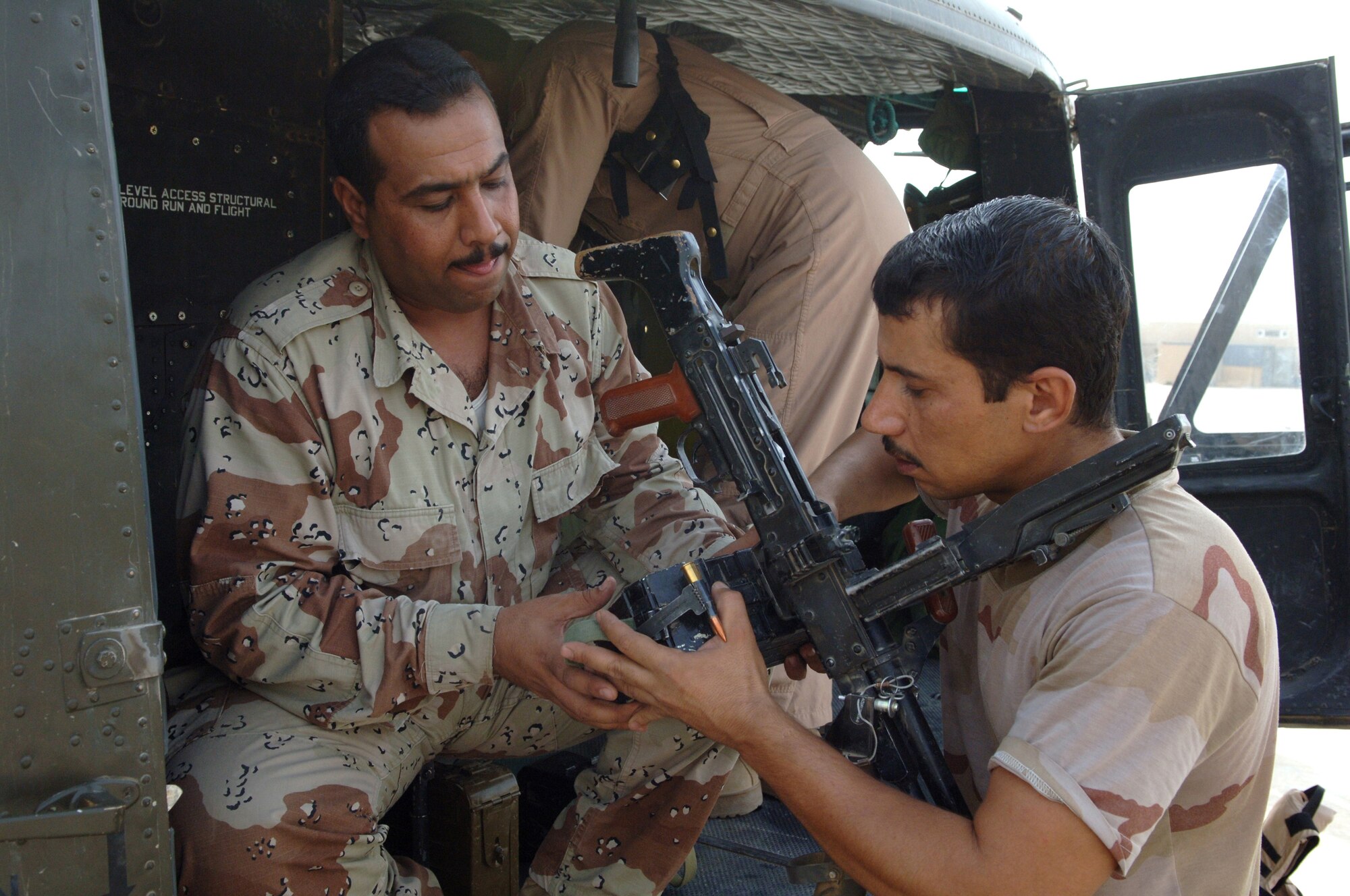 Iraqi air force Pvt. Leath helps Iraqi air force Pvt. Fadhil Faleh prepare for an upcoming training mission at Taji Air Base, Iraq, Sept. 12. Leath is an instructor gunner, and Faleh is an apprentice gunner. Both Iraqi airmen are assigned to 2nd Squadron. (U.S. Air Force photo/Tech. Sgt. Richard Lisum)