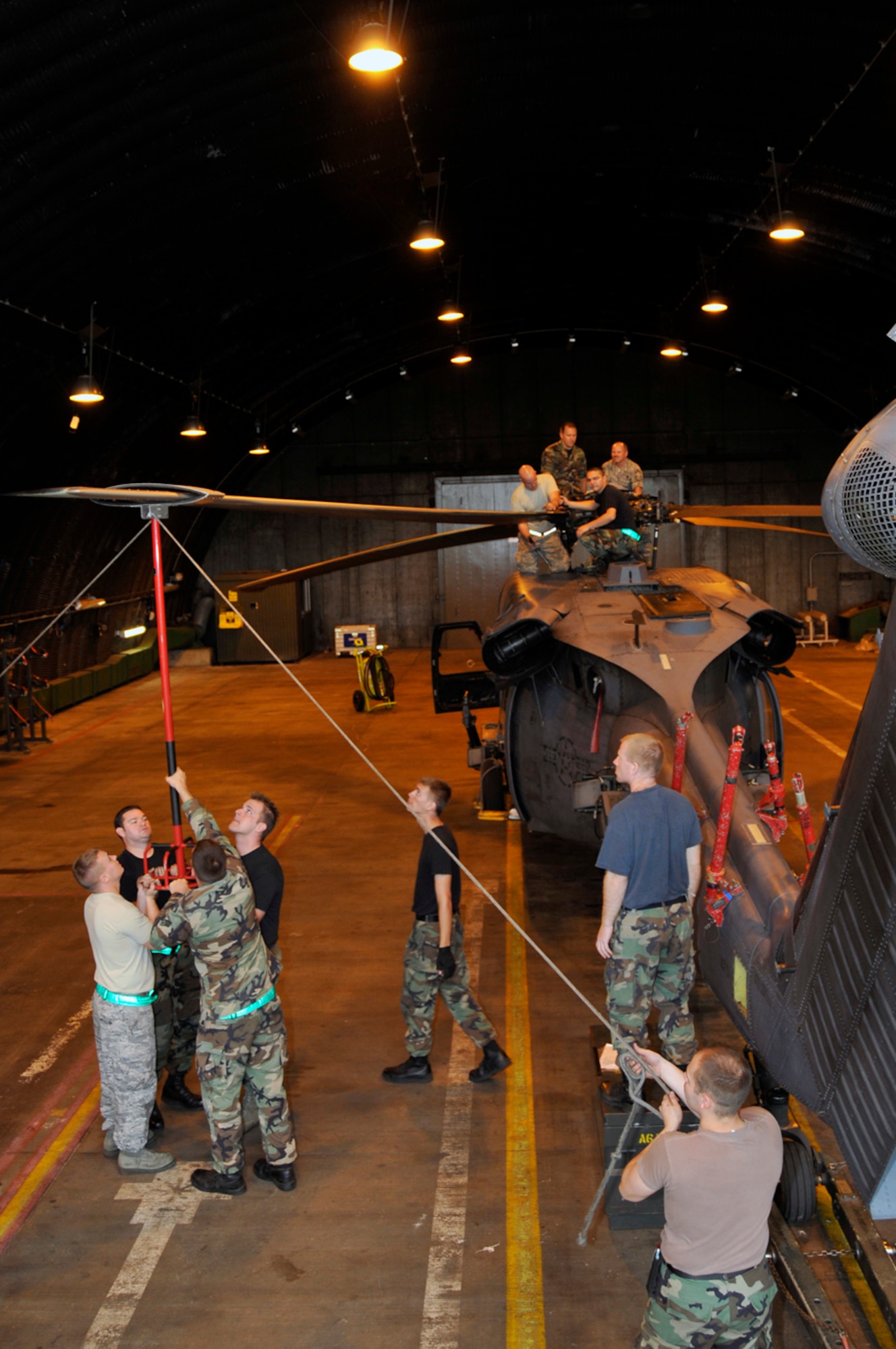 48th Aircraft Maintenance Squadron HH-60G helicopter crew chiefs fold one of the main rotors back to the tail boom adapter Sept. 11 at RAF Lakenheath, England. The "blade pole crew" lift the main rotor blade using a blade pole allowing the crew chief to release the pins that secure the main rotor hub. (U.S. Air Force photo by Airman 1st Class Perry Aston)