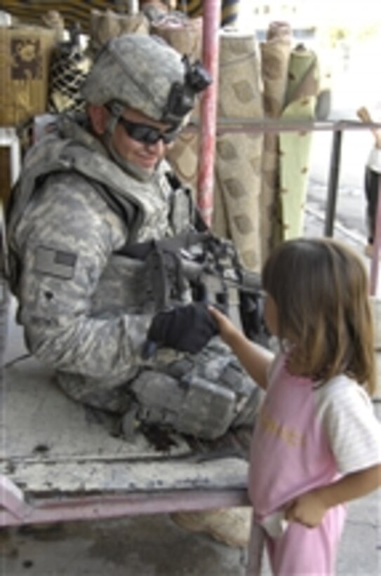 A U.S. Army soldier from 1st Battalion, 8th Infantry Regiment, shakes hands with a young Iraqi girl during an assessment at Cherry Market in Al Karama, Mosul, Iraq, on Sept. 17, 2008.  