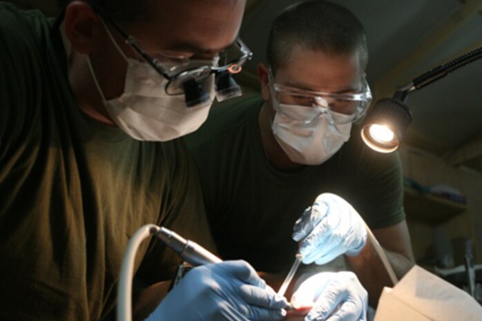 Navy Lt. Chris Beale (left), a dental surgeon in training, and Seaman Brian Wolf, a hospitalman, both with 2nd Combat Logistics Battalion, work together on a patient at the new dental facility on Combat Outpost Rawah, Iraq, Sept. 24. The facility has served more than 140 patients since it opened Sept. 3.