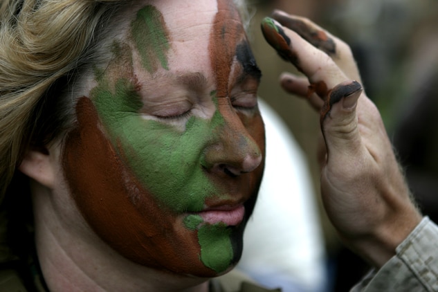 A Marine with U.S. Marine Corps Forces, Special Operations Command, Marine Special Operations Support Group, paints a spouse’s face with camouflage paint during the MSOSG Jane Wayne Day in front of the Goettge Field House here, Sept. 24.