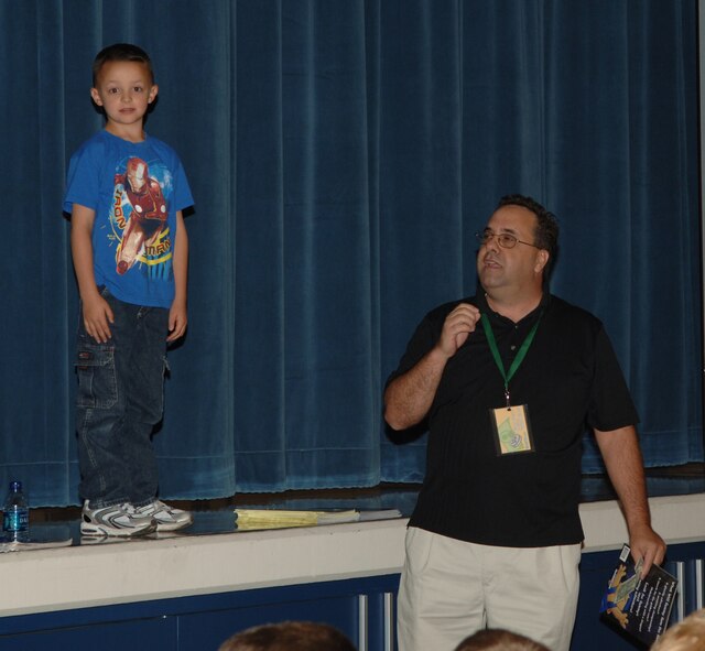 FAIRCHILD AIR FORCE BASE, Wash. – Alexander Kelley, third grader at Michael Anderson Elementary School looks into the camera as he makes his promise to spend the dollar he just earned on his education. Sam X Renick, founder and CEO of “It’s A Habit!” Company, visited Michael Anderson Sept. 23 to spread the word on how important it is to save. Alex raised his hand and got called to the front to answer a question. With the correct answer he received a book and one dollar with the stipulation that he must promise to spend the dollar on his education. (U.S. Air Force photo / Senior Airman Jocelyn A. Ford)