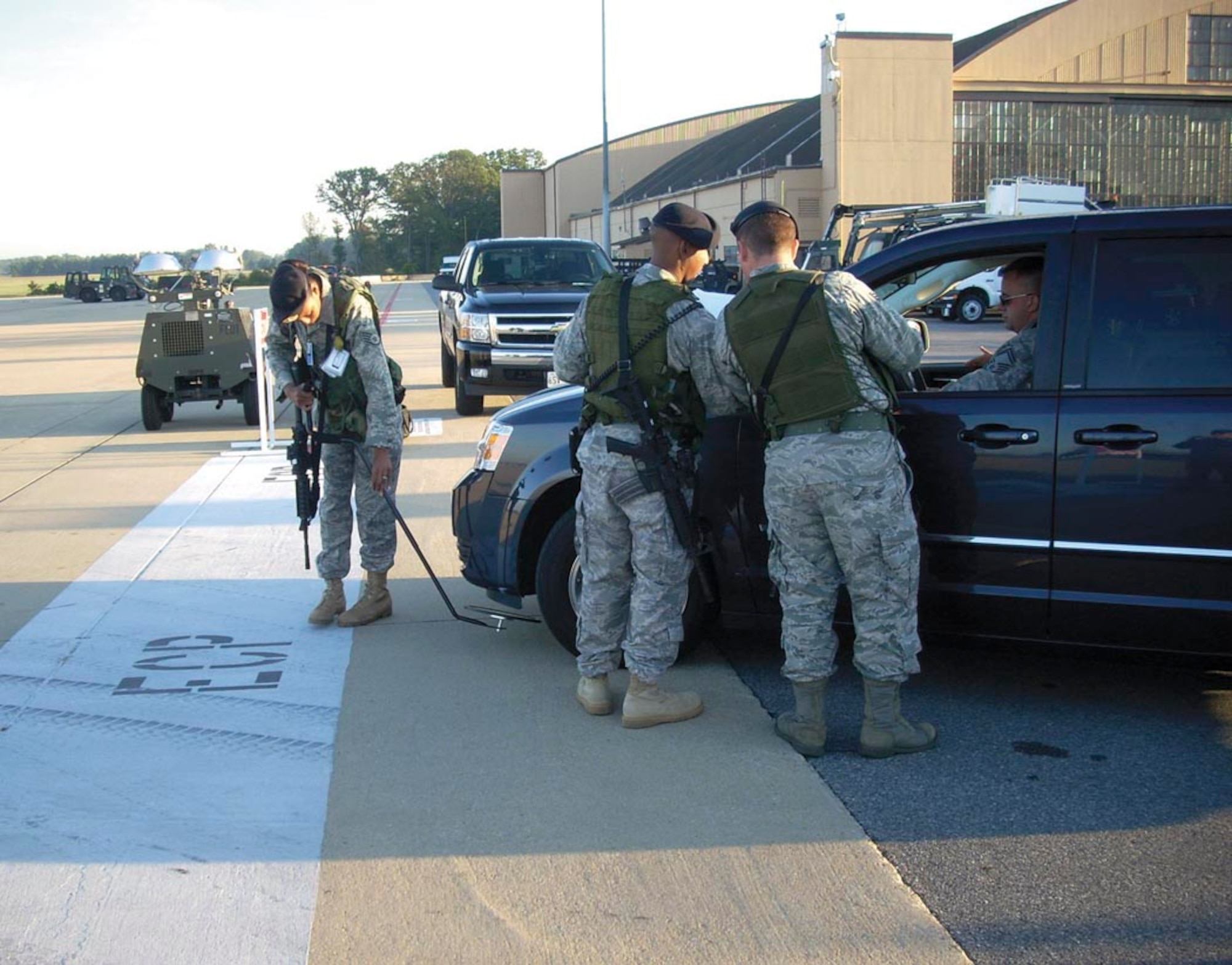 Staff Sgt. Cyrene Gerard, 459th Security Forces Squadron security specialist, performs a vehicle inspection while two other security forces Airmen talk to the driver during the 459th's Nuclear Operational Readiness Inspection held Sept. 19-21. (USAF courtesy photo)