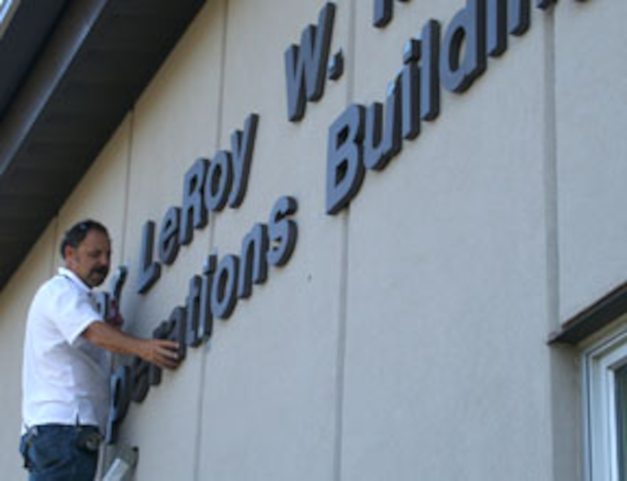 WRIGHT-PATTERSON AFB, Ohio - Roger Peters of Signs Now in Beavercreek, Ohio, affixes the letters to the 445th Airlift Wing’s new operations building.  The building is scheduled to be dedicated Oct. 4, 2008 in honor of Maj. LeRoy W. Homer, Jr., who died on United Flight 93 on Sept. 11, 2001.  He was the first officer on that flight.  (Air Force photo/Capt. Caroline Wellman)