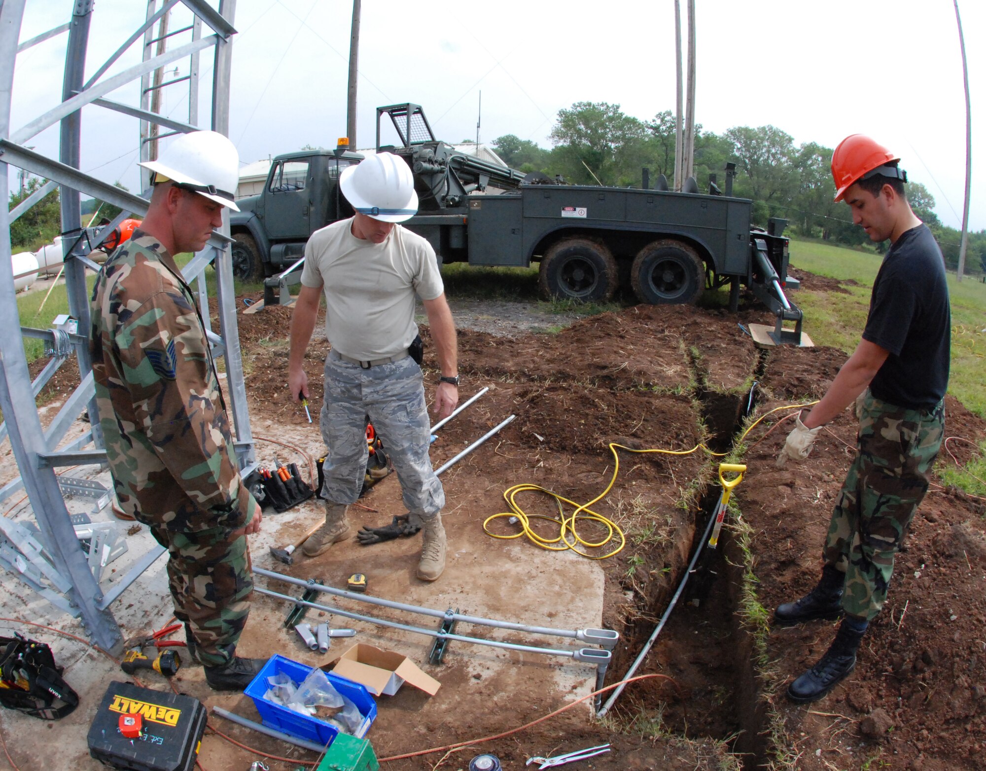 MCCONNELL AIR FORCE BASE, Kan. -- Tech. Sgt.  Jason Olewnik, Staff Sgt. Ernest Crook, and Staff Sgt. Michael Zamora, 22nd Civil Engineer Squadron, install and connect ground wire to a ground to air transmit receiver tower, Sept 8. The grounding material is designed to dissipate lightning strikes to protect the communication equipment on the tower. (photo by Airman 1st Class Jessica Lockoski)