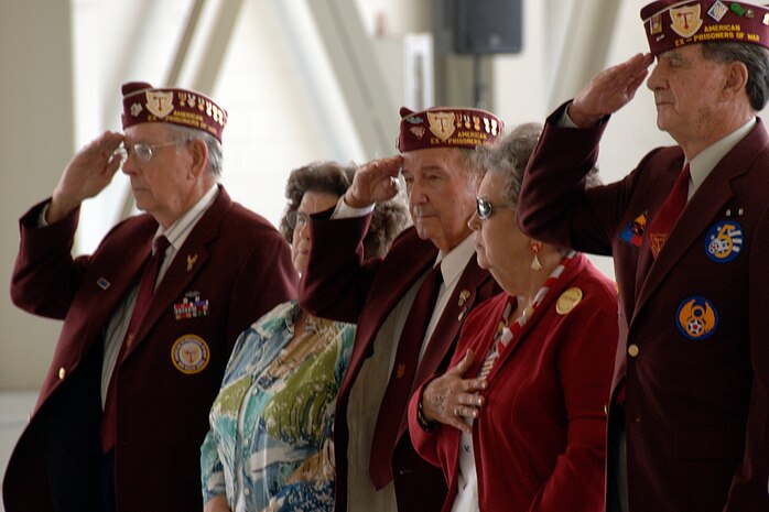 Former POWs and their wives stand at attention and salute the U.S. flag during the playing of the national anthem in nose dock two Sept. 24. Charleston AFB commemorated their brothers in arms who had become prisoners of war or were declared missing in action during a time of war. (U.S. Air Force photo/Airman 1st Class Timothy Taylor)