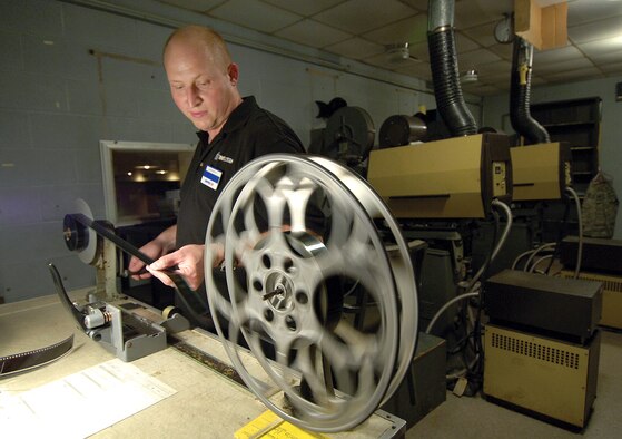 Staff Sgt. Jerry Harding, 3rd Combat Communications Squadron, works as a projectionist for AAFES on weekends at the base theater. He learned while he was stationed at Aviano Air Base, Italy. He says the smell of popcorn gets really thick in the projection booth. He can’t lose focus, this movie had six reels and he has to change one every 20 minutes. Sergeant Harding works to 11:30 p.m. (Air Force photo/Margo Wright)