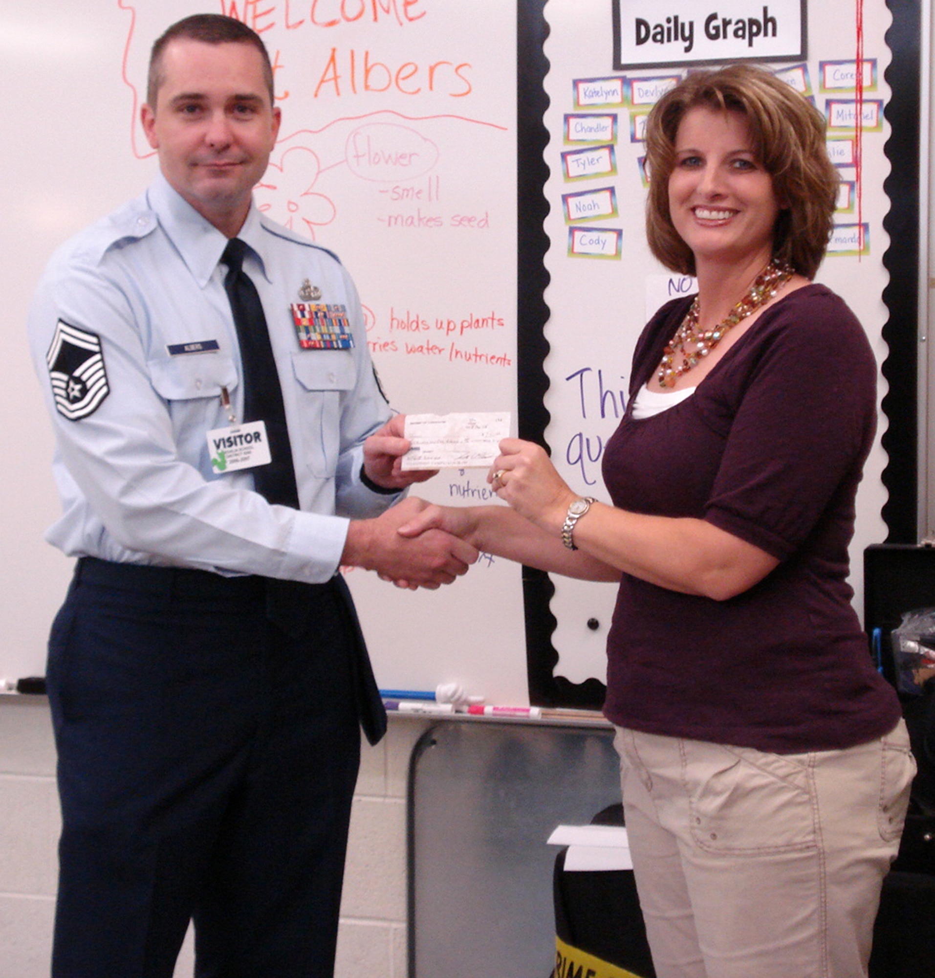 WHITEMAN AIR FORCE BASE, Mo. – Senior Master Sgt. Ron Albers, Top 3 president, passes a $250 scholarship grant to Mrs. Michelle Steger, wife of Master Sgt. Christopher Steger, 509th Logistics Readiness Squadron, Aug. 15. The applications were open to active duty, reserve component enlisted personnel or their immediate family members.  The winners were selected based on their academic achievement, financial need and their education goals. (Photo printed with permission of Master Sgt. Martin Barr)  