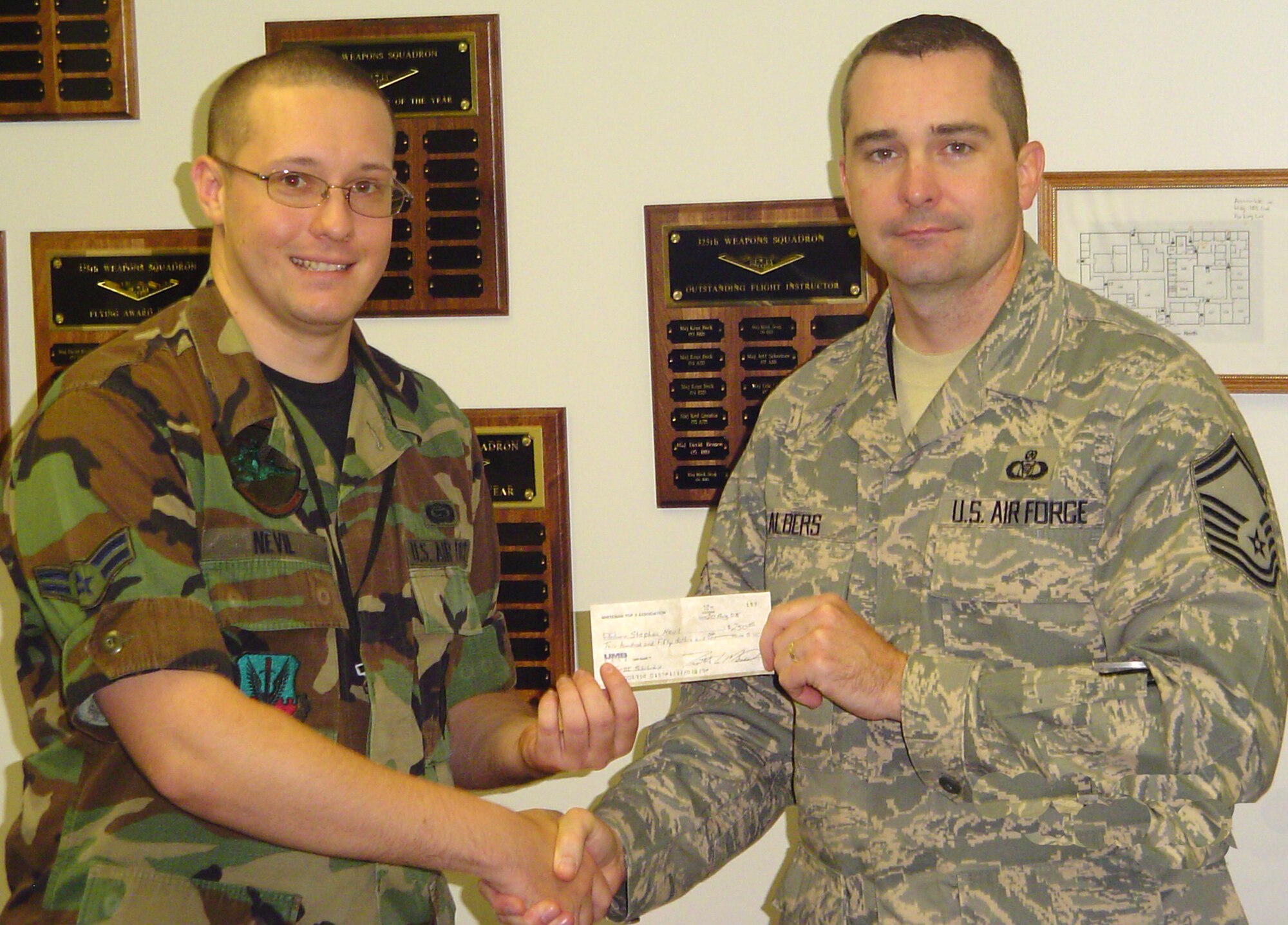 WHITEMAN AIR FORCE BASE, Mo. – Senior Master Sgt. Ron Albers, Top 3 president, passes a $250 scholarship grant to Airman 1st Class Stephen Nevil, 325th Weapons Squadron, Aug. 20. The applications were open to active duty, reserve component enlisted personnel or their immediate family members.  The winners were selected based on their academic achievement, financial need and their education goals. (Photo printed with permission of Master Sgt. Martin Barr)  