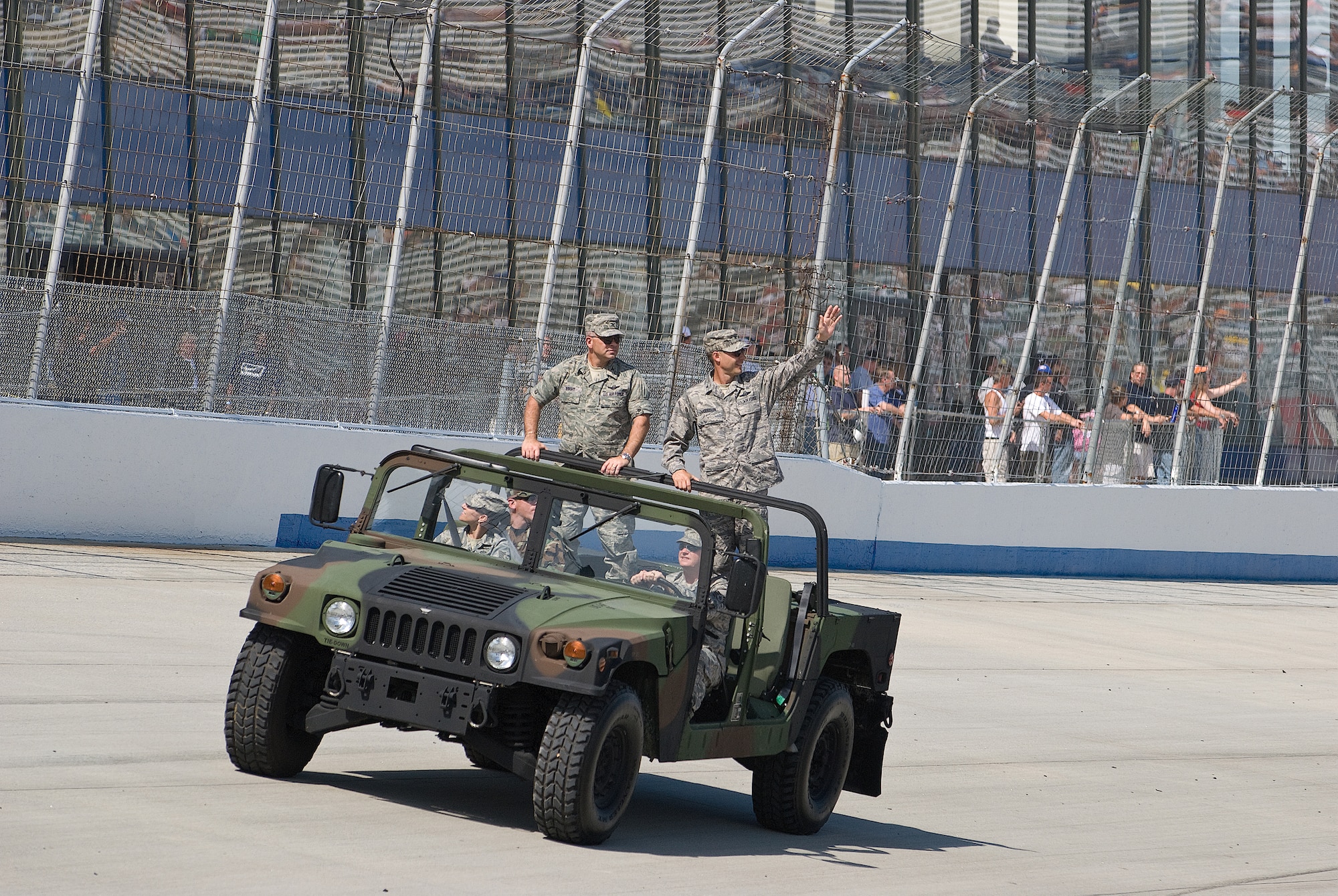 DOVER, Del -- (Left to right) Col. Randal Bright and Col. Steven Harrison, 512th and 436th Airlift Wings commanders, wave to the crowd from the back of a humvee during the parade lap at Dover Downs Sunday immediately before the race. The humvee was driven by members of the 436th Civil Engineer Squadron Explosive Ordnance Disposal Flight. (U.S. Air Force photo/Roland Balik) 
