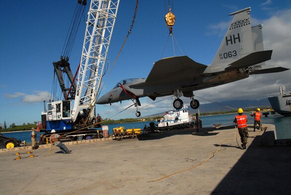 A decommissioned F-15 from the 154 Wing, Hawaii Air National Guard is hoisted onto a barge for delivery to the Pacific Aviatio.