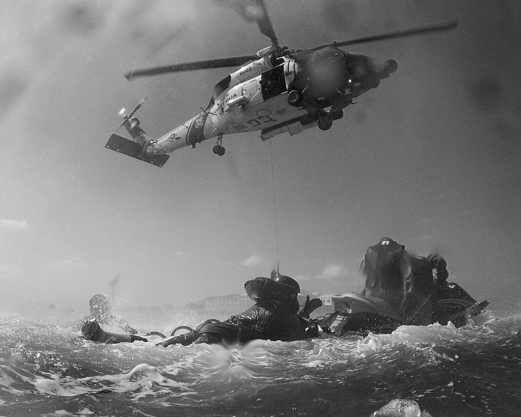 LANGLEY AIR FORCE BASE, Va. -- An HH-60 Jayhawk rescue helicopter from Coast Guard Air Station Elizabeth City, N.C., provides support for water survival training by hoisting students from the water to the helicopter in simulated rescue Sept. 18.  The training, conducted by 1st Operations Support Squadron Survival, Evasion, Resistance and Escape specialists, teaches students how to survive if they egress over water.  Students learn how to endure life in a 20-man raft, a seven-man raft and a one-man raft, as well as how to best utilize a survival kit.  The course covers proper signaling, desalinating water, finding sustenance and how to properly release from a parachute drag.  Pilots are required to complete water survival training every three years.  (U.S. Air Force photo/Senior Airman Christopher L. Ingersoll)