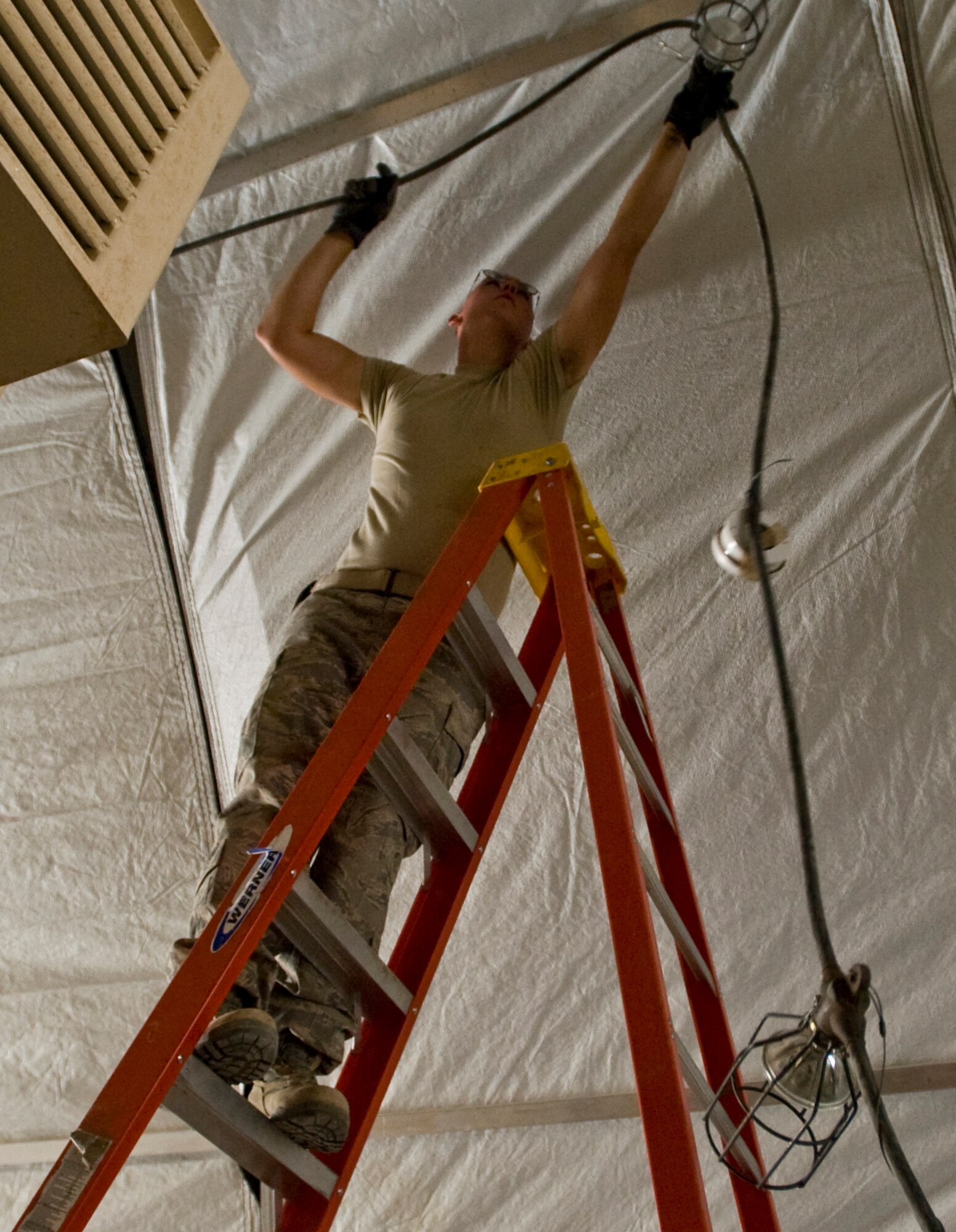 ALI BASE, Iraq -- Airman 1st Class Zackery Hopper, 407th Expeditionary Civil Engineer Squadron electrician, installs light fixtures Sept. 24, 2008. With the relocation of the force protection facility, Airmen in the 407th ECES Power Pro shop are installing a new power supply and light fixtures. Hopper is deployed from F.E. Warren Air Force Base, Wyo. (U.S. Air Force photo/Airman 1st Class Christopher Griffin)