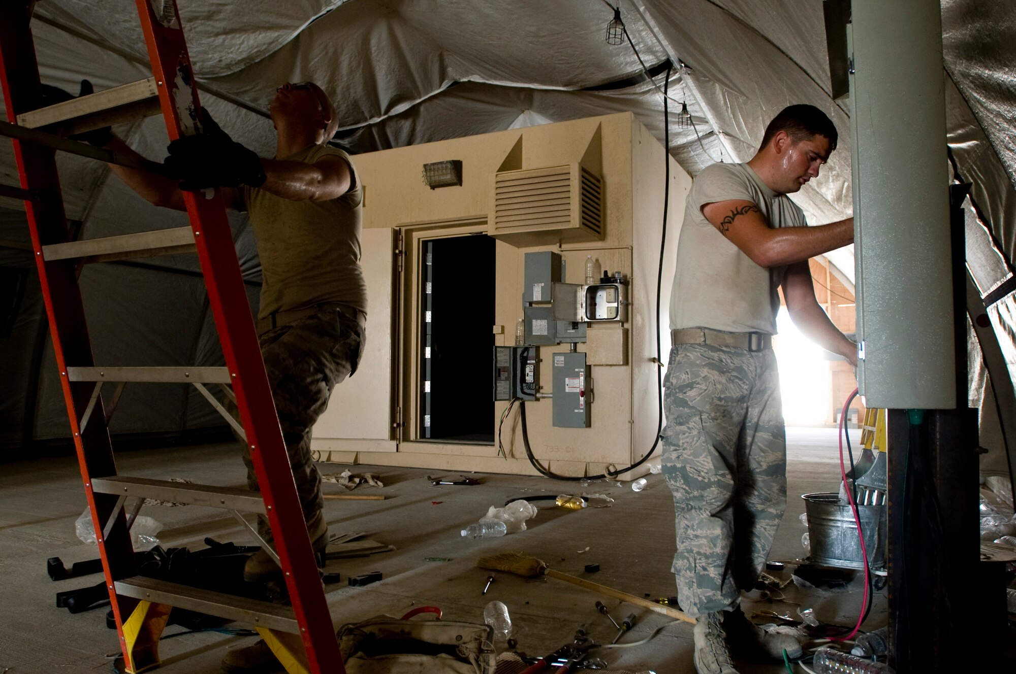 ALI BASE, Iraq -- Airman 1st Class Zackery Hopper and Senior Airman Curtis Barnhill, 407th Expeditionary Civil Engineer Squadron electricians, provide power to the new force protection facility Sept. 24, 2008. With the relocation of the force protection facility, Airmen in the 407th ECES Power Pro shop are installing a new power supply and light fixtures. Hopper and Barnhill are deployed from F.E. Warren Air Force Base, Wyo. (U.S. Air Force photo/Airman 1st Class Christopher Griffin)