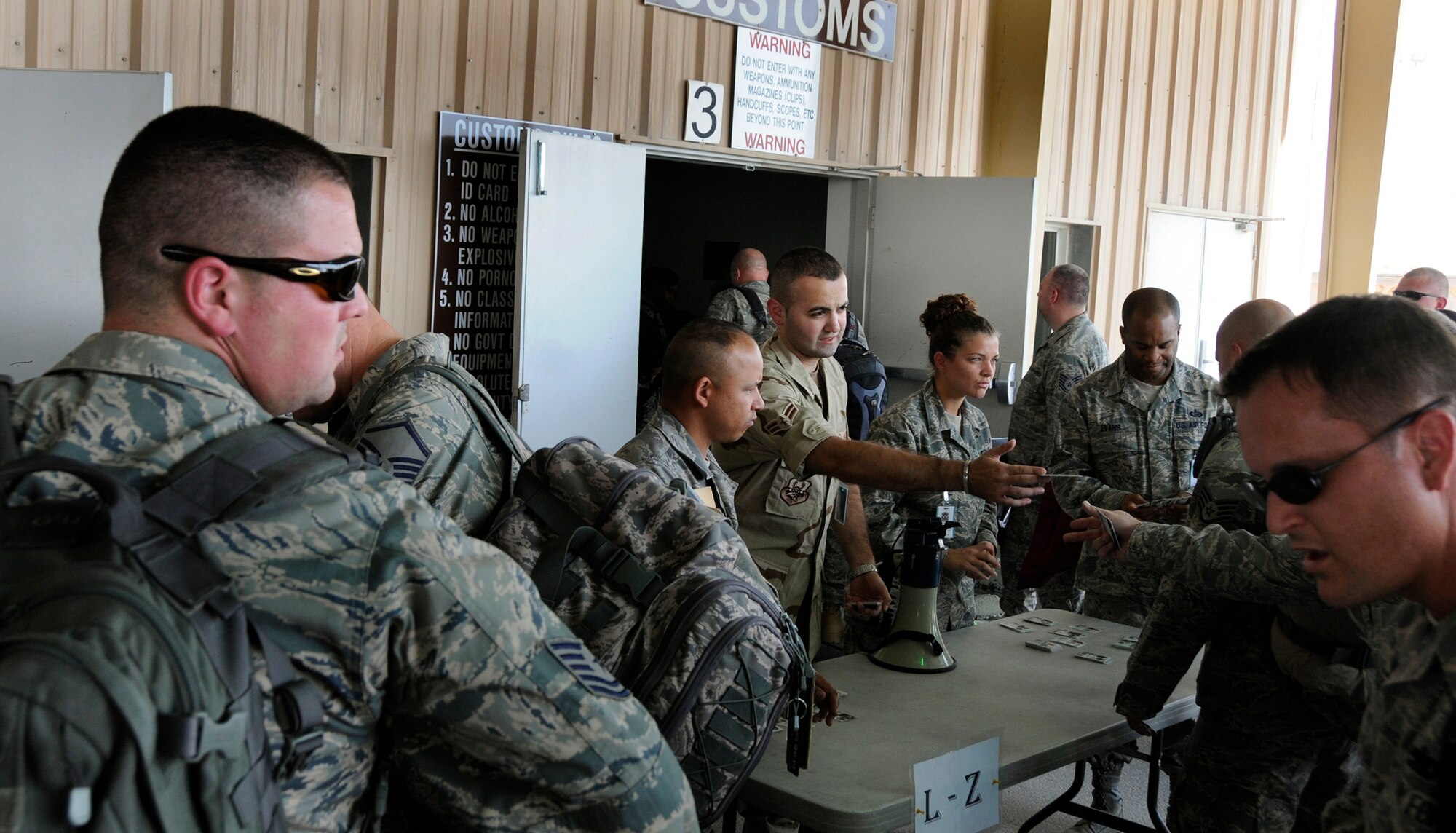 Airman 1st Class Zana Hikmat, 379th Expeditionary Force Support Squadron, Personnel Support for Contingency Operations (PERSCO), hands identification cards to new arrivals after they have cleared through customs Sept. 24, 2008.  Personnel deployed in Air Expeditionary Force 5/6 are rotating into this undisclosed air base in Southwest Asia. The PERSCO team is responsible for the in-processing and out-processing of personnel and providing 100% accountability of U.S. military, civilian & coalition forces assigned to the base in support of Operations Iraqi and Enduring Freedom and Joint Task Force-Horn of Africa.  Airman Hikmat is deployed from Hanscom Air Force Base, Mass.  (U.S. Air Force photo by Tech. Sgt. Michael Boquette/Released)