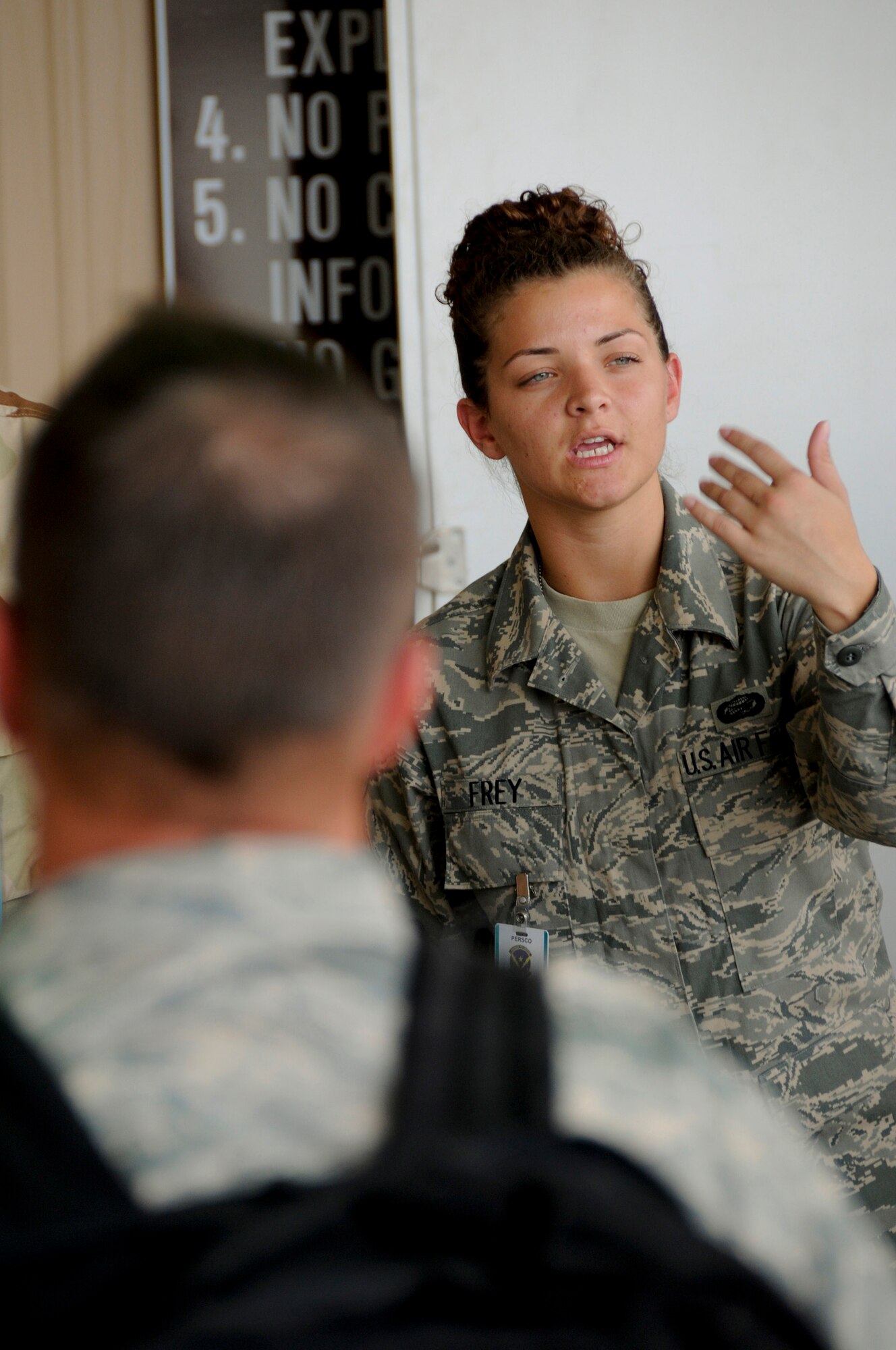 Airmen 1st Class Kourtney Frey, 379th Expeditionary Force Support Squadron, Personnel Support for Contingency Operations (PERSCO), waves the next airman up to pick up identification cards during in-processing Sept. 24, 2008.  Personnel deploying in Air Expeditionary Force 5/6 are rotating into this undisclosed air base in Southwest Asia. The PERSCO team is responsible for the in-processing and out-processing of personnel and providing 100% accountability of U.S. military, civilian & coalition forces assigned to the base.  Airman Frey is deployed from Westover Air Reserve Base, Mass., in support of Operations Iraqi and Enduring Freedom and Joint Task Force-Horn of Africa.  (U.S. Air Force photo by Tech. Sgt. Michael Boquette/Released)