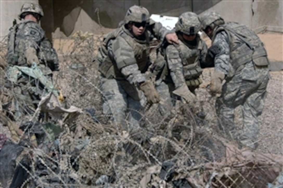 U.S. Army soldiers drag concertina wire to a collection point at Joint Security Station Gazaliyah IV while conducting a cleanup operation in the Gazaliyah district, Baghdad, Iraq, Sept. 22, 2008. The soldiers are assigned to the 101st Airborne Division's 1st Squadron, 75th Cavalry Regiment, 2nd Brigade Combat Team .