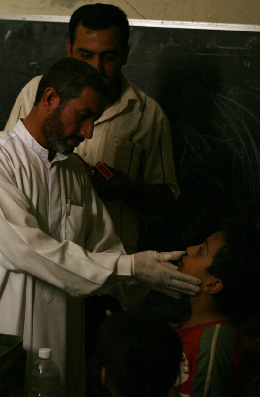 GORTAN, Iraq (September 25, 2008) – An Iraqi doctor feels a boys throat after he complained of soreness during a Combined Medical Engagement (CME) held by Company C, Task Force 1st Battalion, 2nd Marine Regiment, Regimental Combat Team 1, Sept. 25. The CME was held after sunset out of respect for the Muslim holiday of Ramadan and allowed Iraqis to obtain medical care if needed. (Official U.S. Marine Corps photo by Lance Cpl. Scott Schmidt)