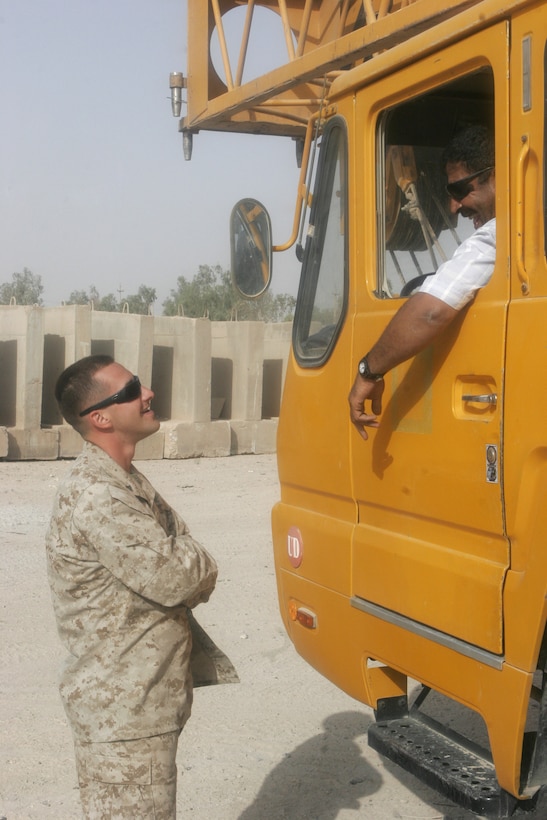 Lance Cpl. Gregory Jeranek, operations non-commissioned officer for I Marine Expeditionary Force Headquarters Group (Forward), practices speaking Arabic with an Iraqi contractor crane operator while talking about the next task for the day on Camp Fallujah, Iraq, Sept. 26. (Photo and caption by Cpl. Daniel Angel.)