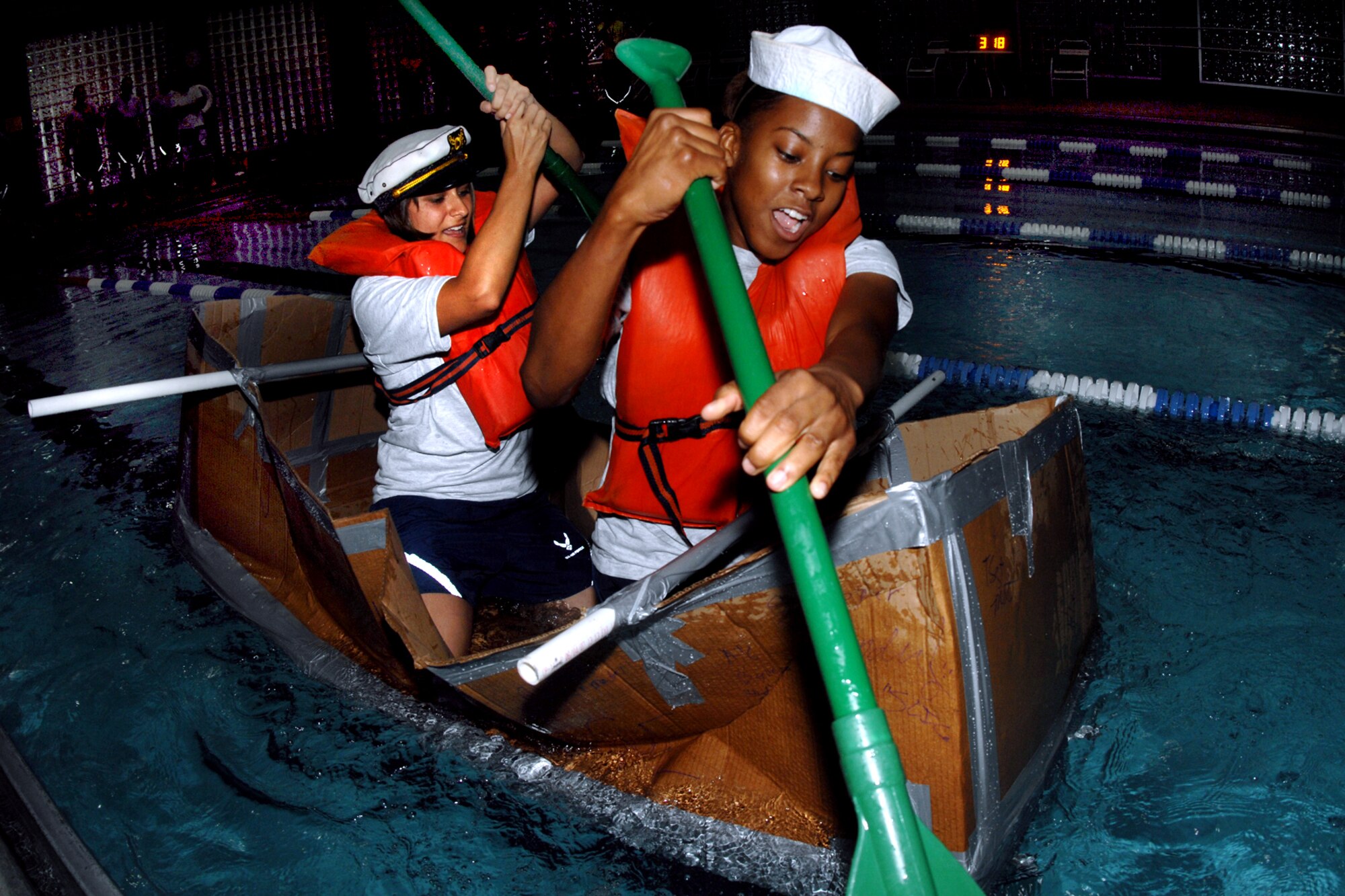 Airman 1st Class Eugenia Heart and Staff Sgt. Kelly Bender, 55th Maintenance Squadron, paddle through the rough waters of the Offutt Field House indoor lap pool during the Card Board Boat Race challenge for Wingman Day on September 25. (U.S. Air Force Photo By Charles Haymond)