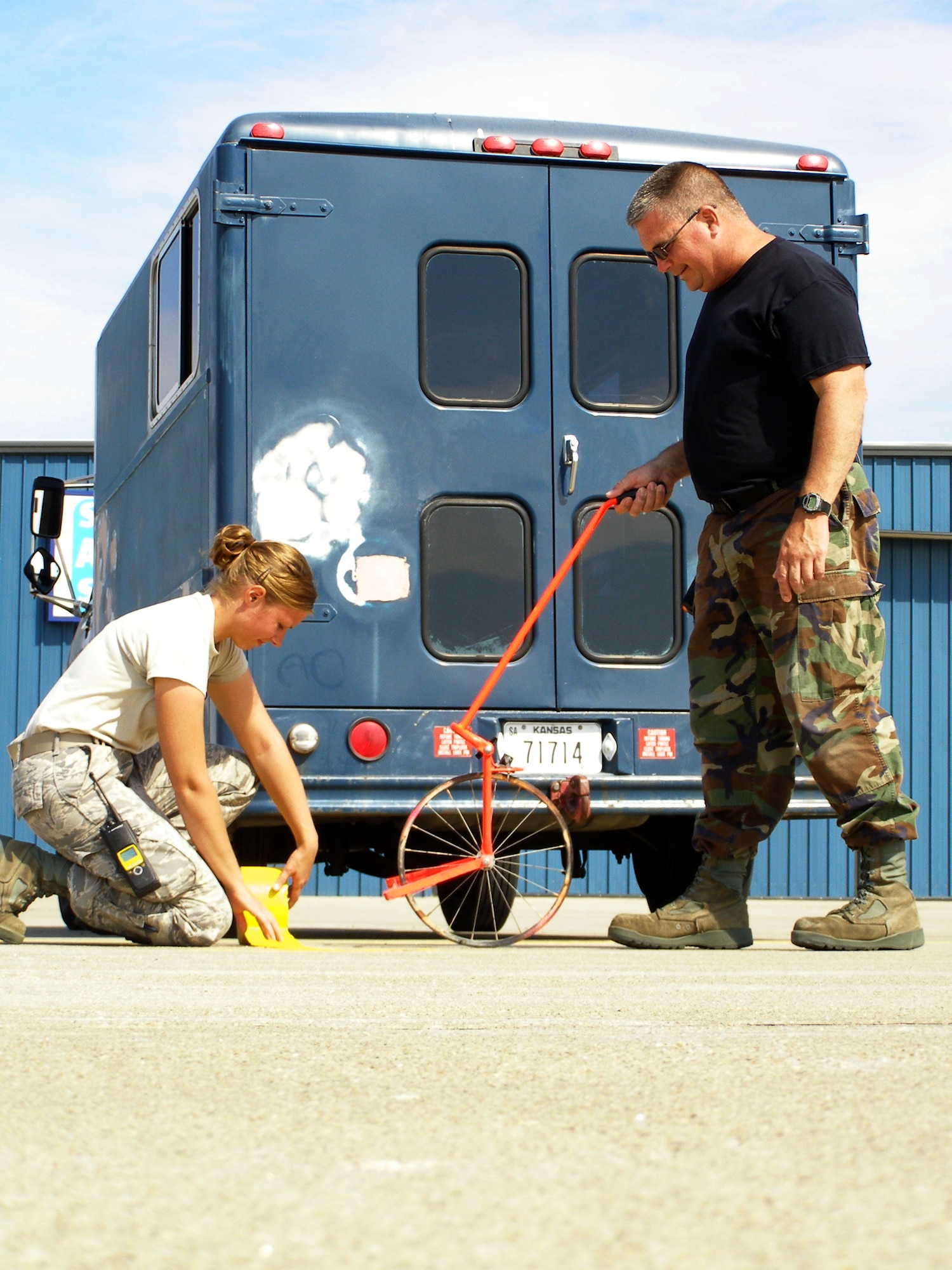Staff Sgt. Sarah Bower and Master Sgt. Mark Shaw apply reflective tape to the flight line at the Salina, Kan., airport Sept. 25, 2008, to prepare for Hawgsmoke 2008, which will be held there Oct. 15 to 18.  Hawgsmoke is a bienniel A-10 bombing and gunnery competition, hosted by the 442nd Fighter Wing, an Air Force Reserve A-10 unit based at Whiteman Air Force Base, Mo.  Sergeant Bower is a member of the the 442nd Aicraft Maintenance Squadron's Specialist Flight and Sergeant Shaw is in the 442nd Maintenance Squadron's Armament Flight.  The tape will be used to mark the taxi paths and parking spots for 75 A-10 aircraft expected for Hawgsmoke 2008.  (U.S. Air Force photo/Maj. David Kurle)