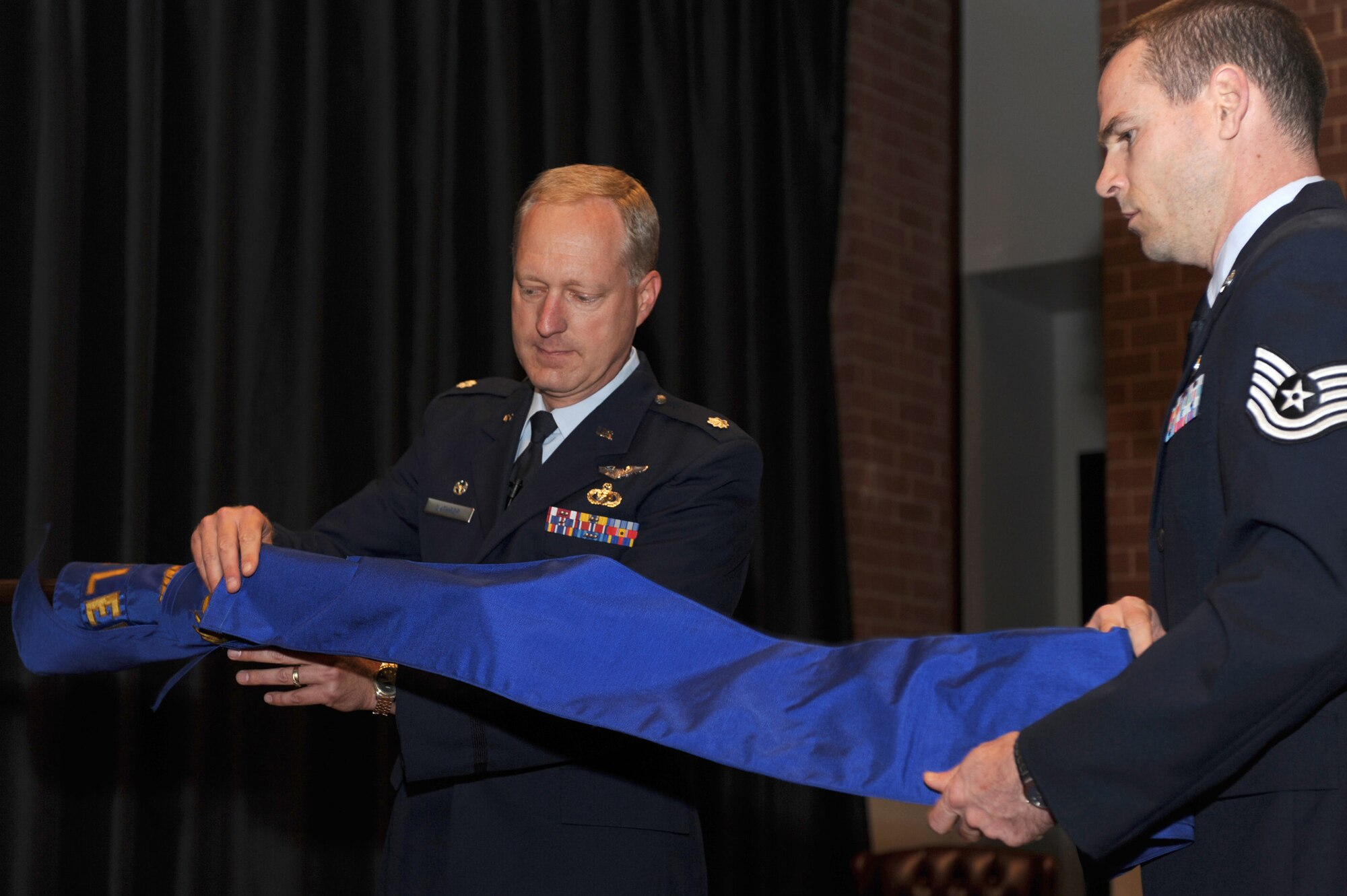Lt. Col. Jeffrey Lathrop, the last commander of the Air Mobility Battlelab, pulls the covering over the flag of the battlelab with the help of Tech. Sgt. Joe Jones during a deactivation ceremony of the battlelab in the U.S. Air Force Expeditionary Center's Grace Peterson Hall Sept. 24, 2008.  The battlelab closed after 10 years.  (U.S. Air Force Photo/Staff Sgt. Nathan Bevier)