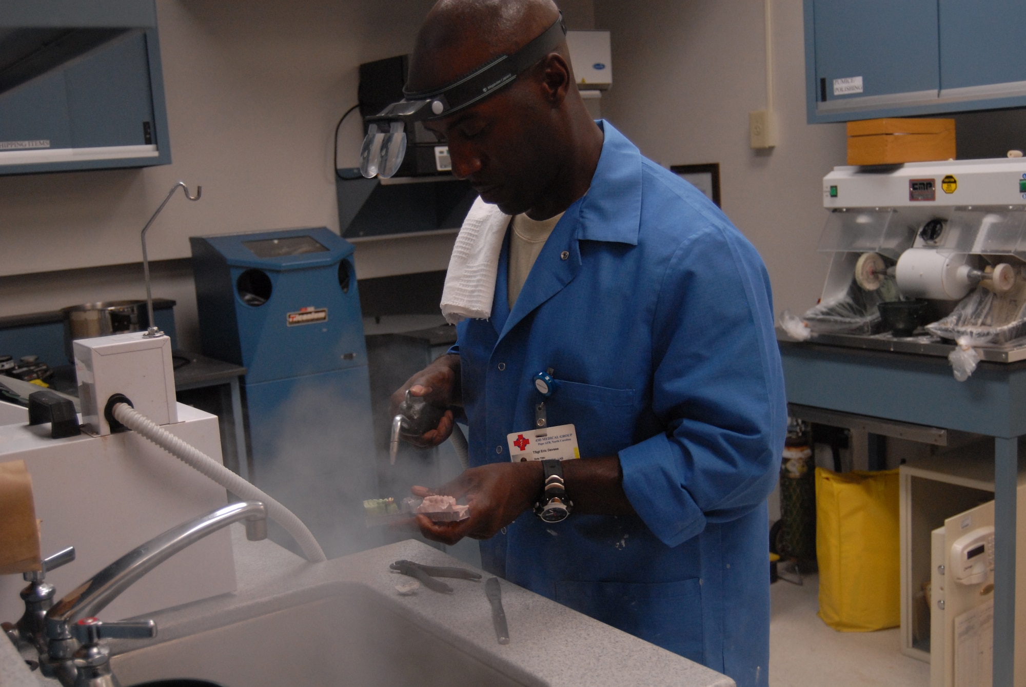 Tech. Sgt. Eric Devese, 43rd Aerospace Medicine Squadron dental laboratory technician, uses the microblaster to air abrade the gold casting with aluminum oxide to recover the crown and remove any remaining investment. (U.S. Air Force Photo by Airman 1st Class Mindy Bloem)
