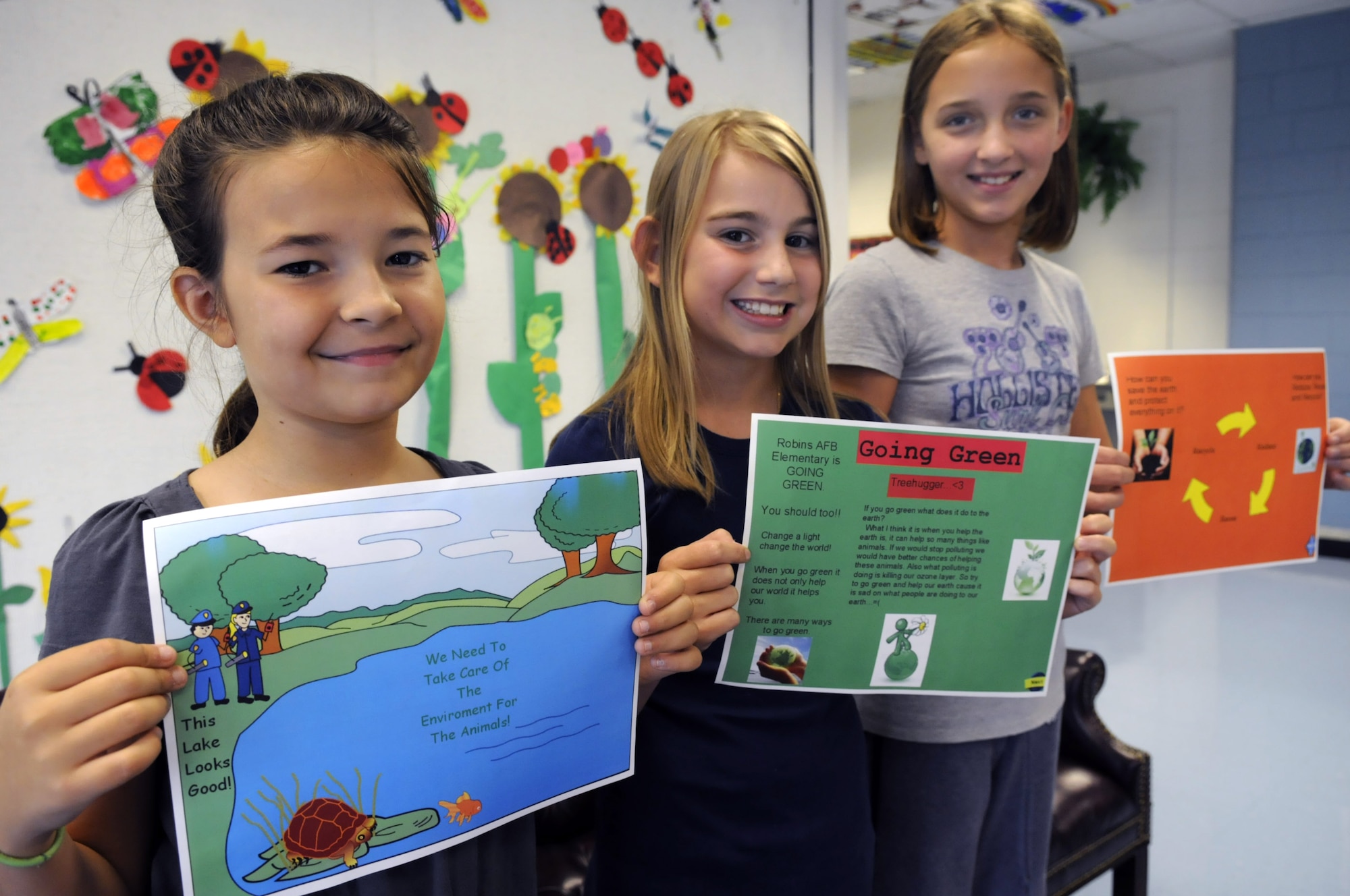 Alyssa Toellner, 4th grade, Brittany Fiveash and Kelsey Badgett, 6th grade, show off their Going Green advertisements. U. S. Air Force photo by Sue Sapp