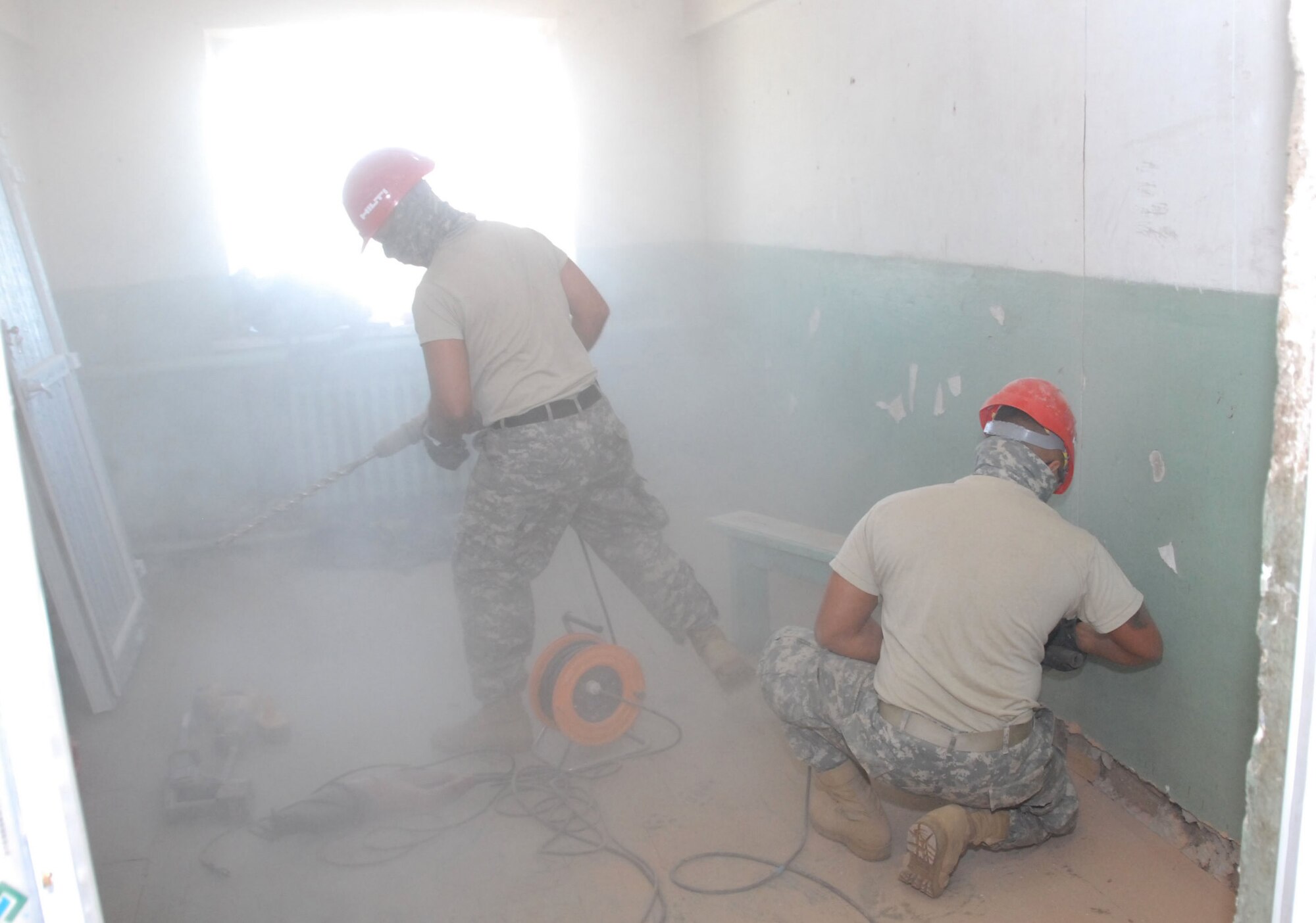 Staff Sergeant Lawrence Pinheiro, carpenter, and Sergeant Joey Fernandez, carpenter, amidst a cloud of dust in the school dormitory in Alton Bulaag, Mongolia, where a renovation project by the 871st Engineering Battalion, Wailuku, Hawaii is underway. The local school dormitory had last been renovated in 1961. The Army Guard plumbers, electricians, masons and carpenters began overhauling windows, doors, paint and flooring on Sept. 4, 2008, with a deadline for completion of Sept. 21. They renovations were part of the field-training exercise Khaan Quest 2008, a United Nations multinational peace support exercise in Mongolia at Camp Five Hills Training Center near Ulaan Baatar. Alaska Air National Guard photo by MSgt. Jules Barklow.