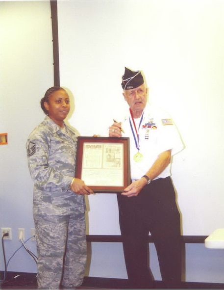 MOODY AIR FORCE BASE, Ga. -- Hank "Sarge" McQuinn presents Master Sgt. Harriet Mallory, 23rd Force Support Squadron career advisor, a framed and signed copy of a two-sided safe conduct pass. Mr. McQuinn possessed the pass for more than 55 years.(Courtesy photo)