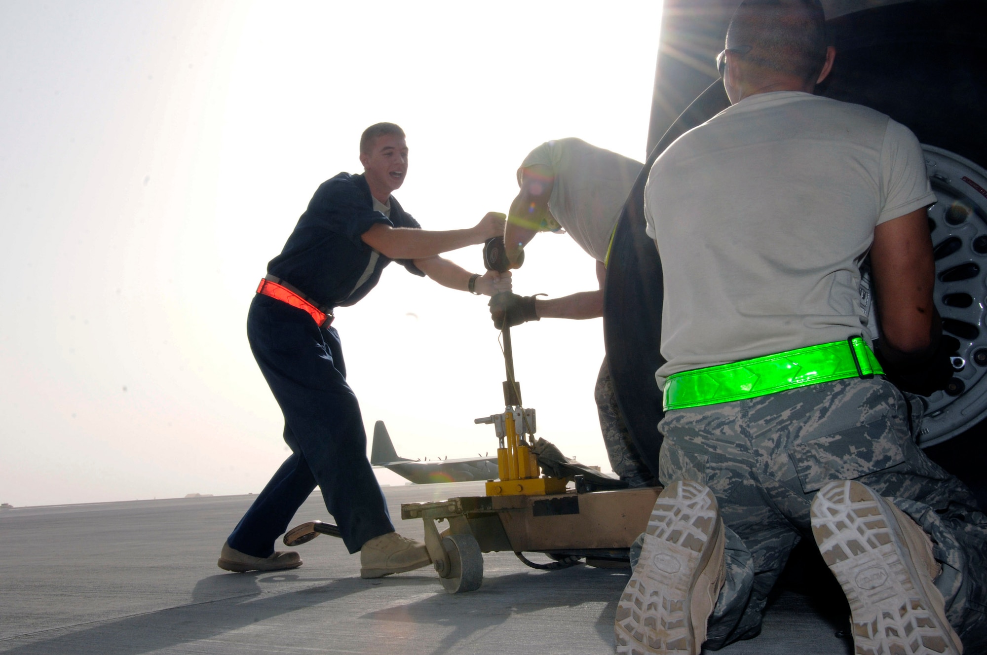 Tech. Sgt. Chris Reiter and Airman 1st Class Ryan McMillen team up on the jack lifting the more than 300,000 pounds of a KC-135 Stratotanker as Airman 1st Class James Giesick removes the dust cover Sept. 28 at an air base in Southwest Asia. The tire needed to be removed and the brake unit replaced after a crack in the heat shield was detected during a post-flight inspection. Sergeant Reiter is assigned to the 340th Aircraft Maintenance Unit. He is a native of Farmington, N.M., is deployed from Fairchild Air Force Base, Wash. Airman Giesick is from San Diego and deployed from Grand Forks AFB, N.D. Airman McMillen is a native of Warsaw, Ill., and deployed from McConnell AFB, Kan. They are assigned to the 340th Aircraft Maintenance Unit. (U.S. Air Force photo/Tech. Sgt. Michael Boquette) 
