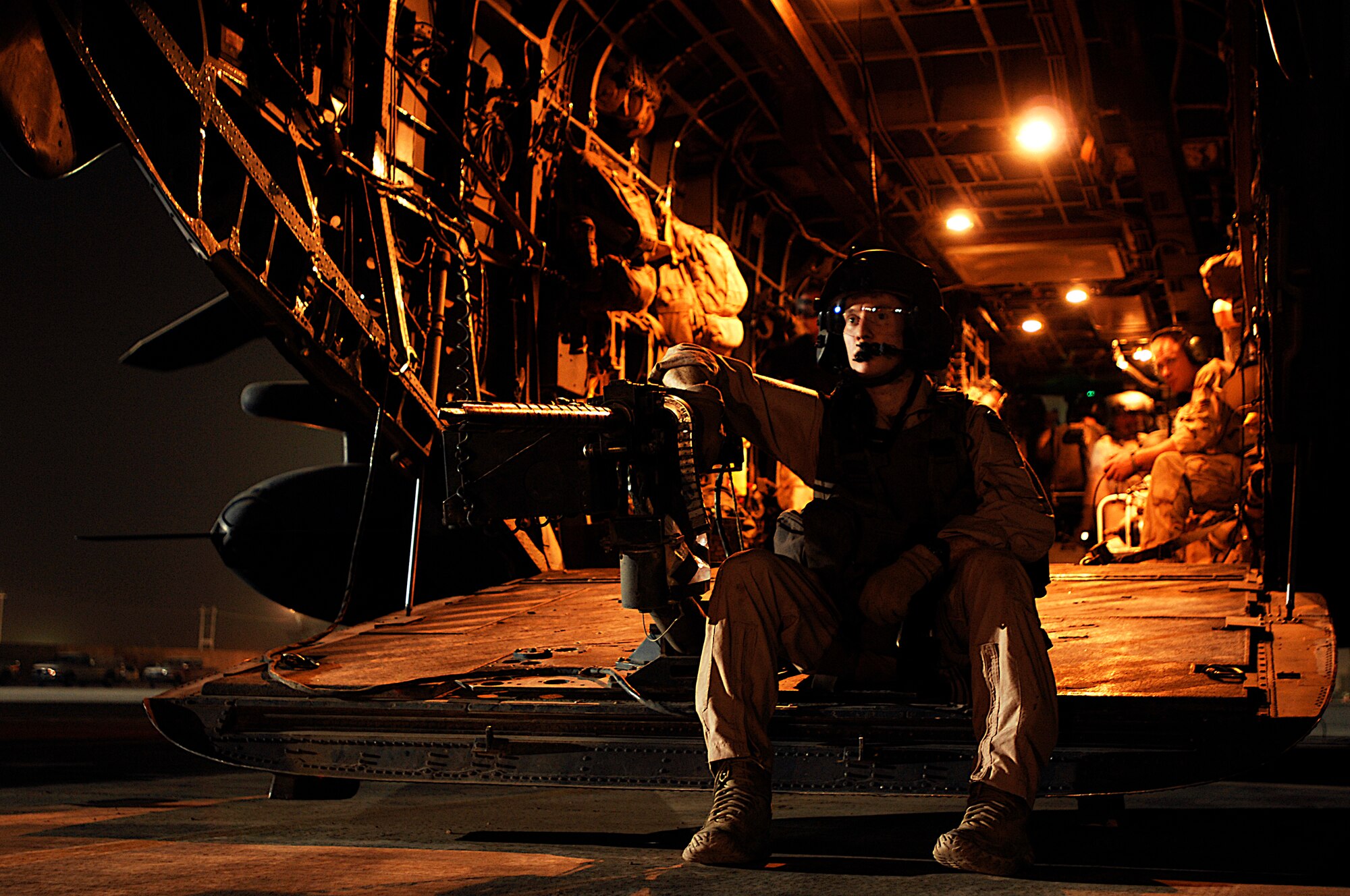 An aerial gunner sits beside a .50-caliber machine gun mounted on the back of an MH-53 Pave Low before conducting his final combat mission on the airframe Sept. 27. The MH-53s' mission was to supply special operations forces in support of Operation Iraqi Freedom. The MH-53 will be retired from the Air Force inventory on Sept. 30. (U.S. Air Force photo/Airman 1st Class Jason Epley)